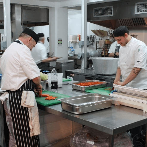 People working in a kitchen with various utensils.