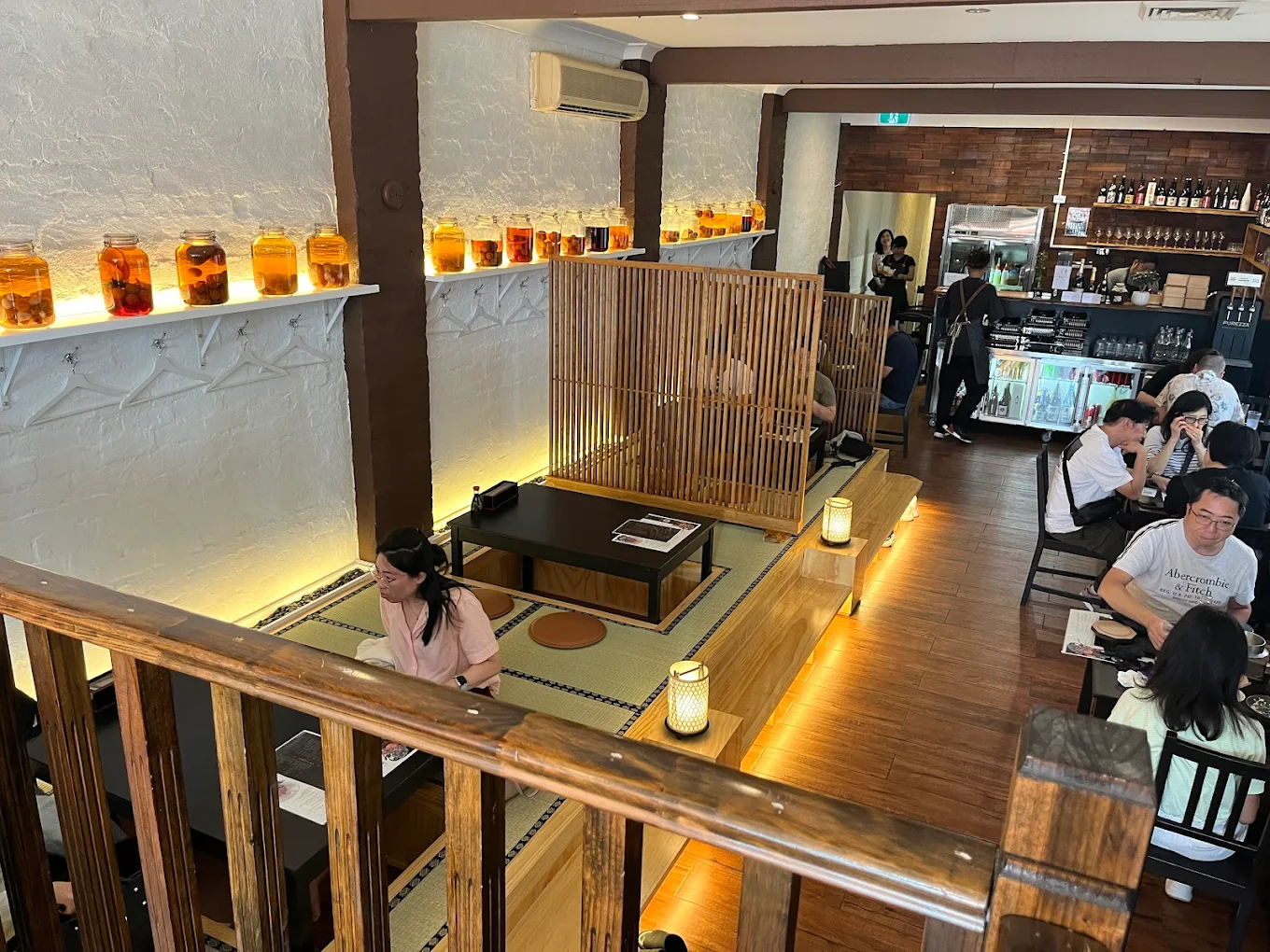 Cozy cafe corner with a round terrazzo table surrounded by wooden chairs, decorated with potted plants and a large mirror reflecting warm light.