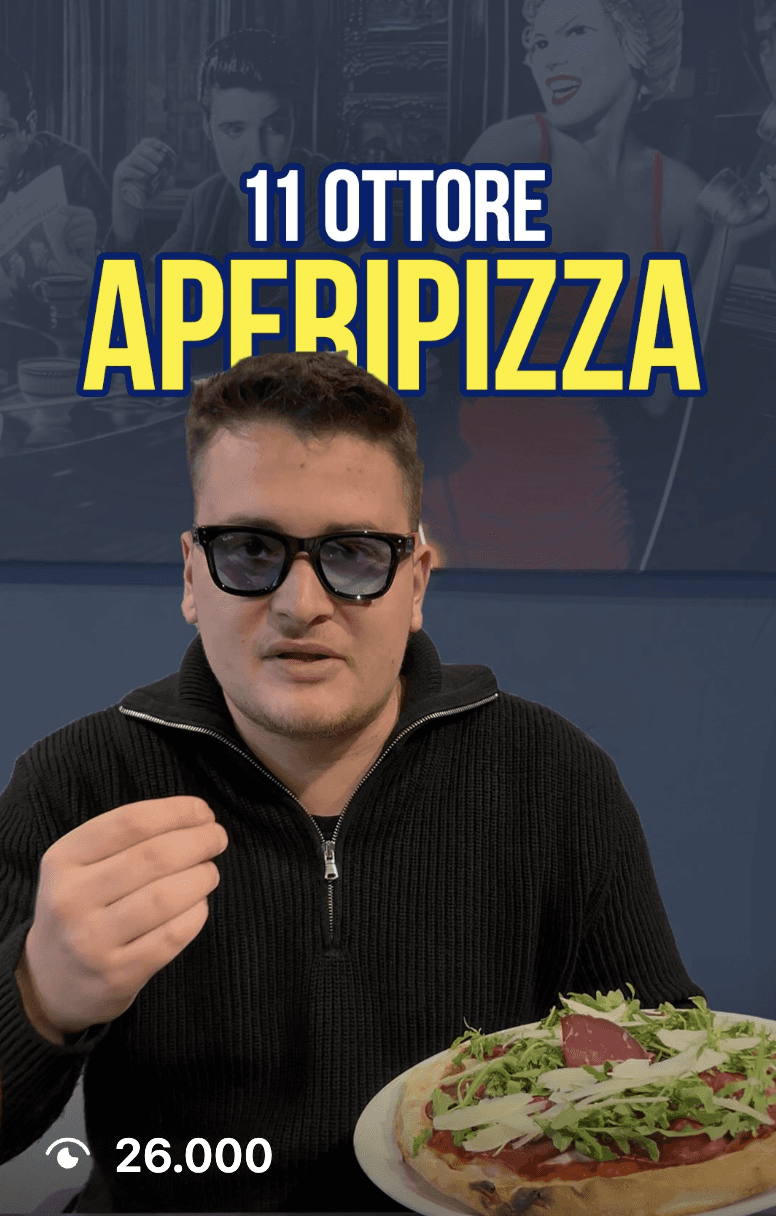 A smiling couple takes a selfie under a clear blue sky. The woman wears a red jacket, and the man, in a green top, holds a smartphone.