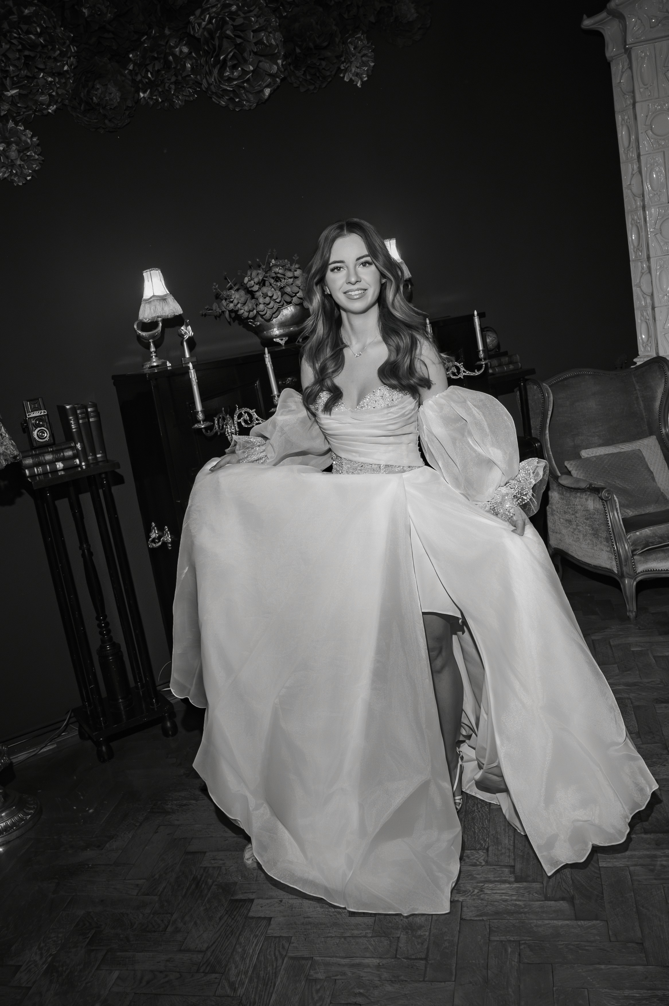 Mireasă zâmbitoare așezată pe fotoliu în decor clasic, lumină caldă, fotografie autentică de nuntă