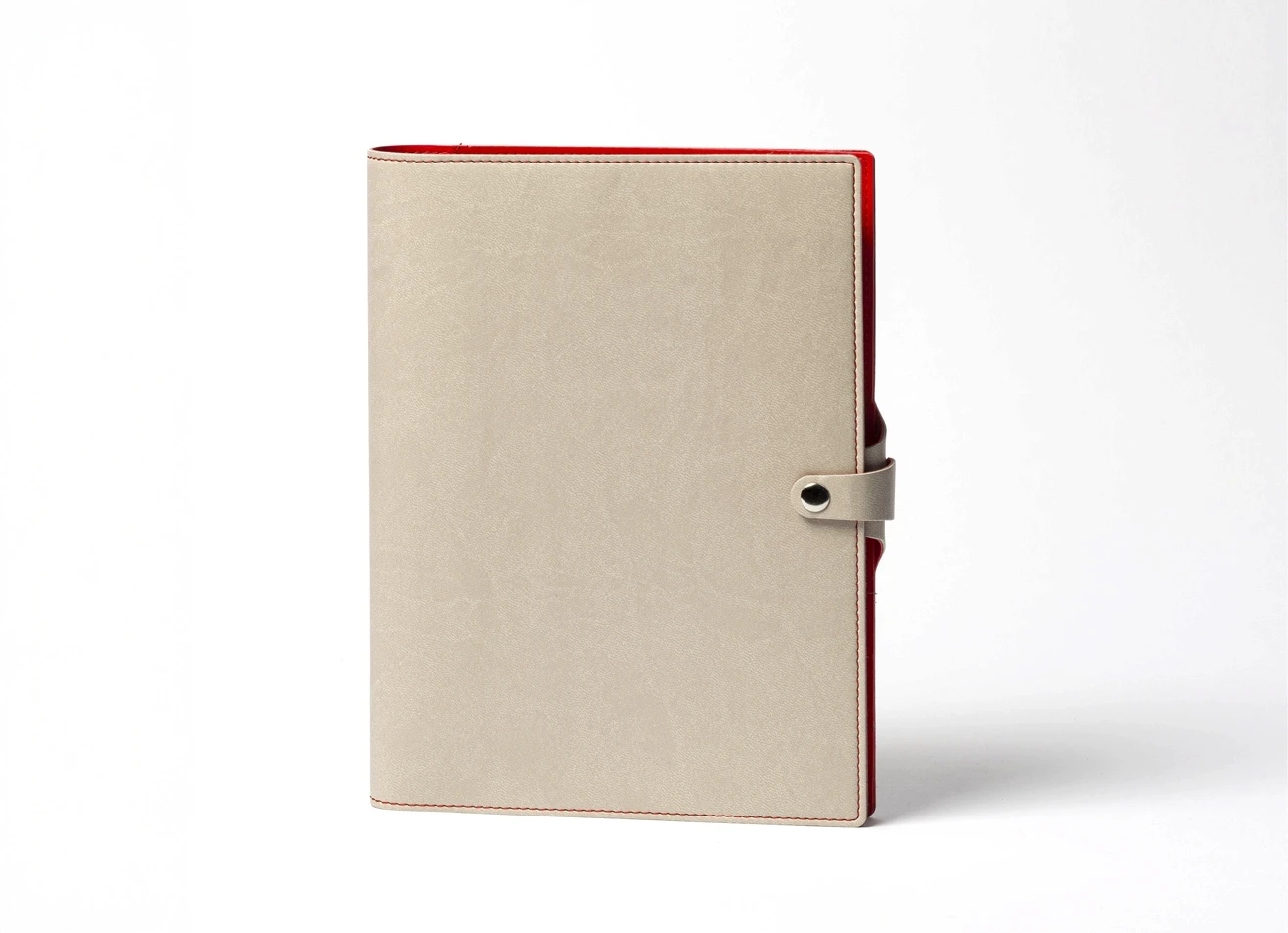 Front view of standing beige notebook with red edges.