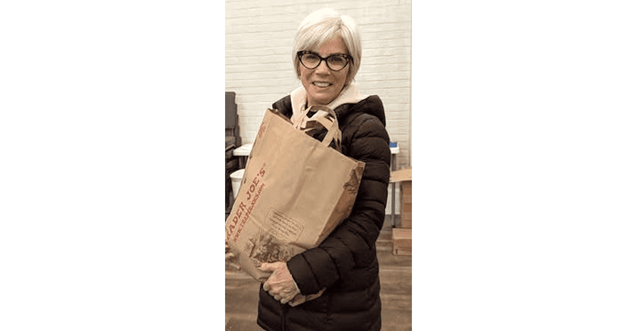 Shalom Food Pantry Volunteer Ellen Weinstein with a bag of supplies for those facing financial strain.