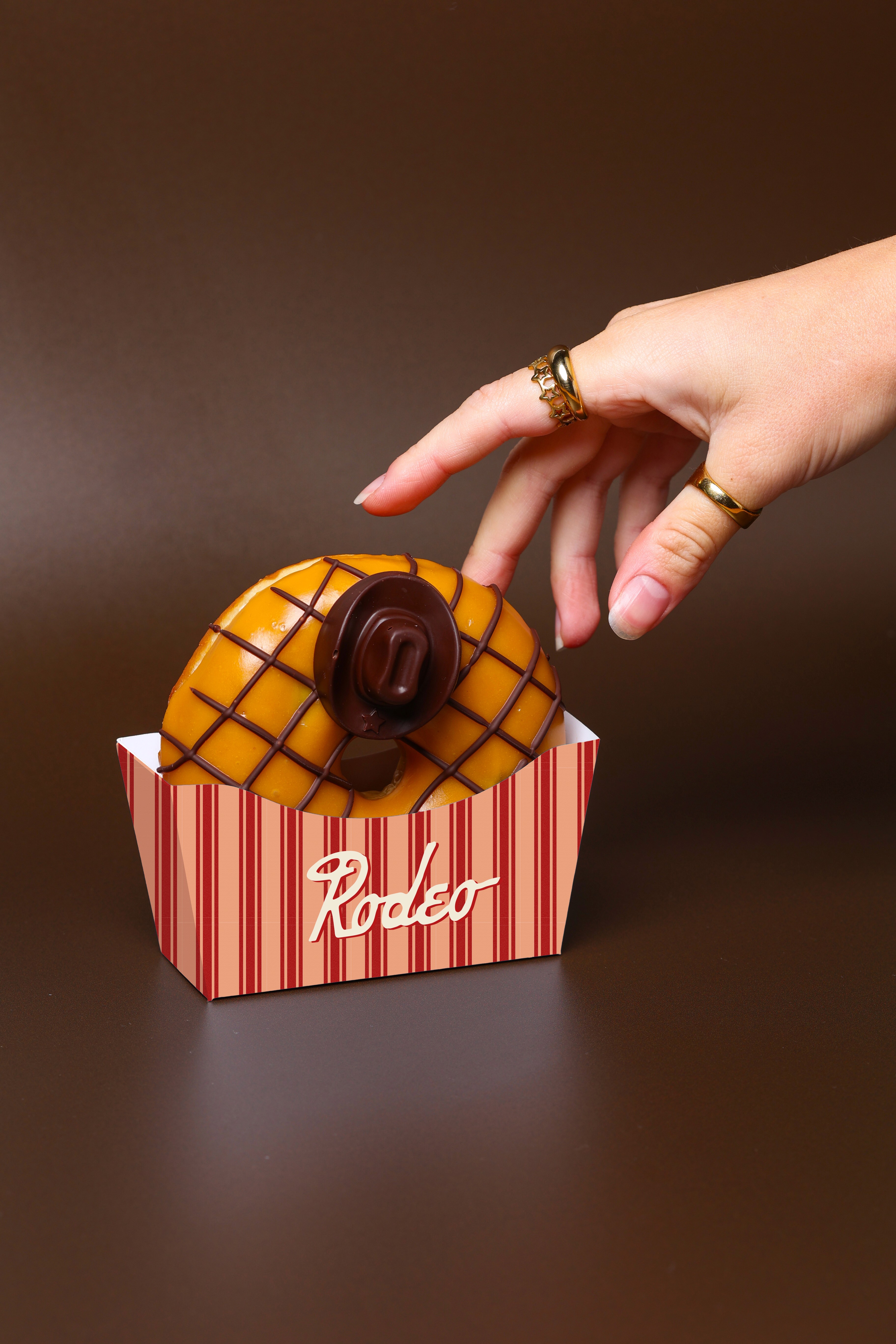 A close up of a hand reaching towards a doughnut.