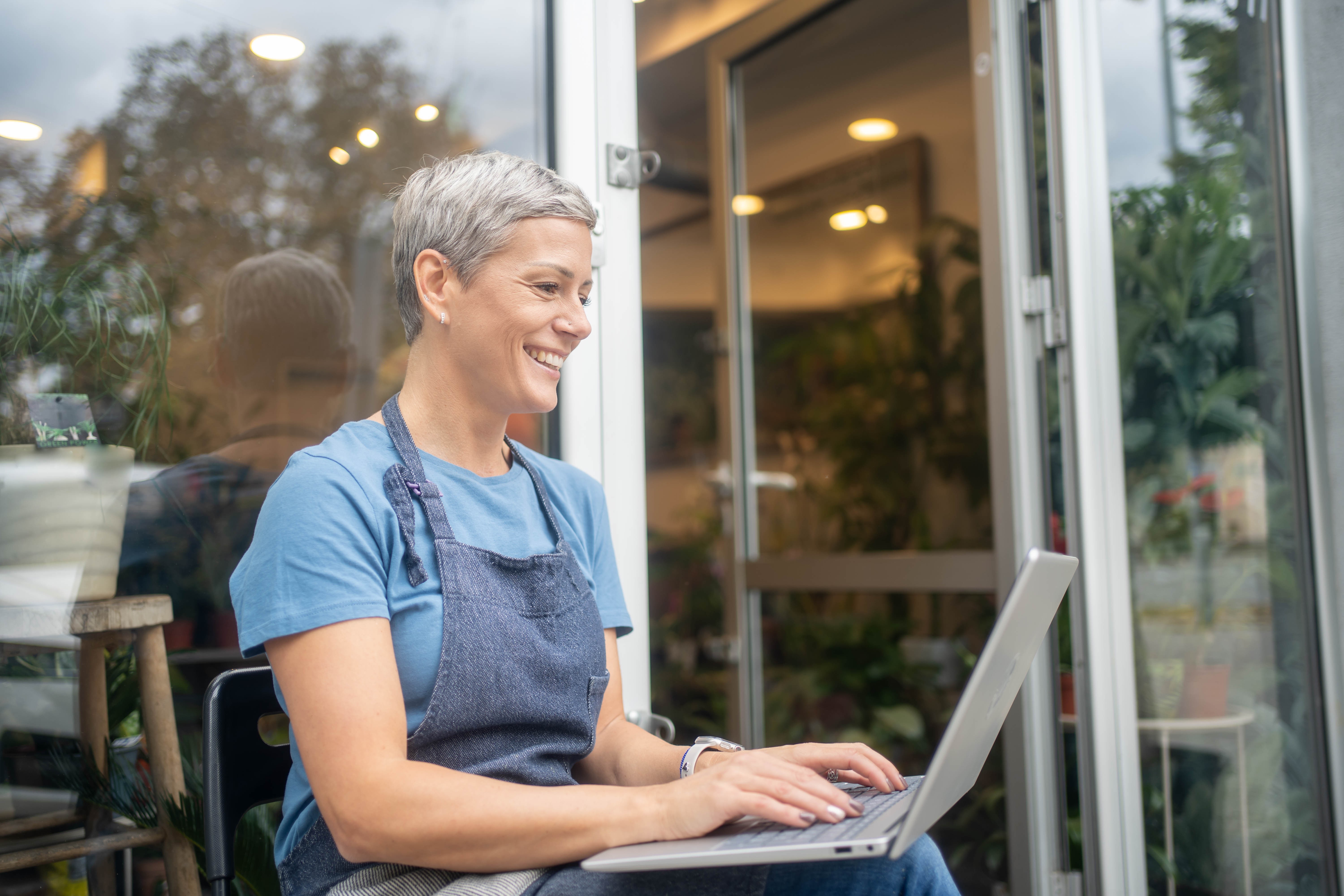 Experienced small business owner working on laptop outside her shop