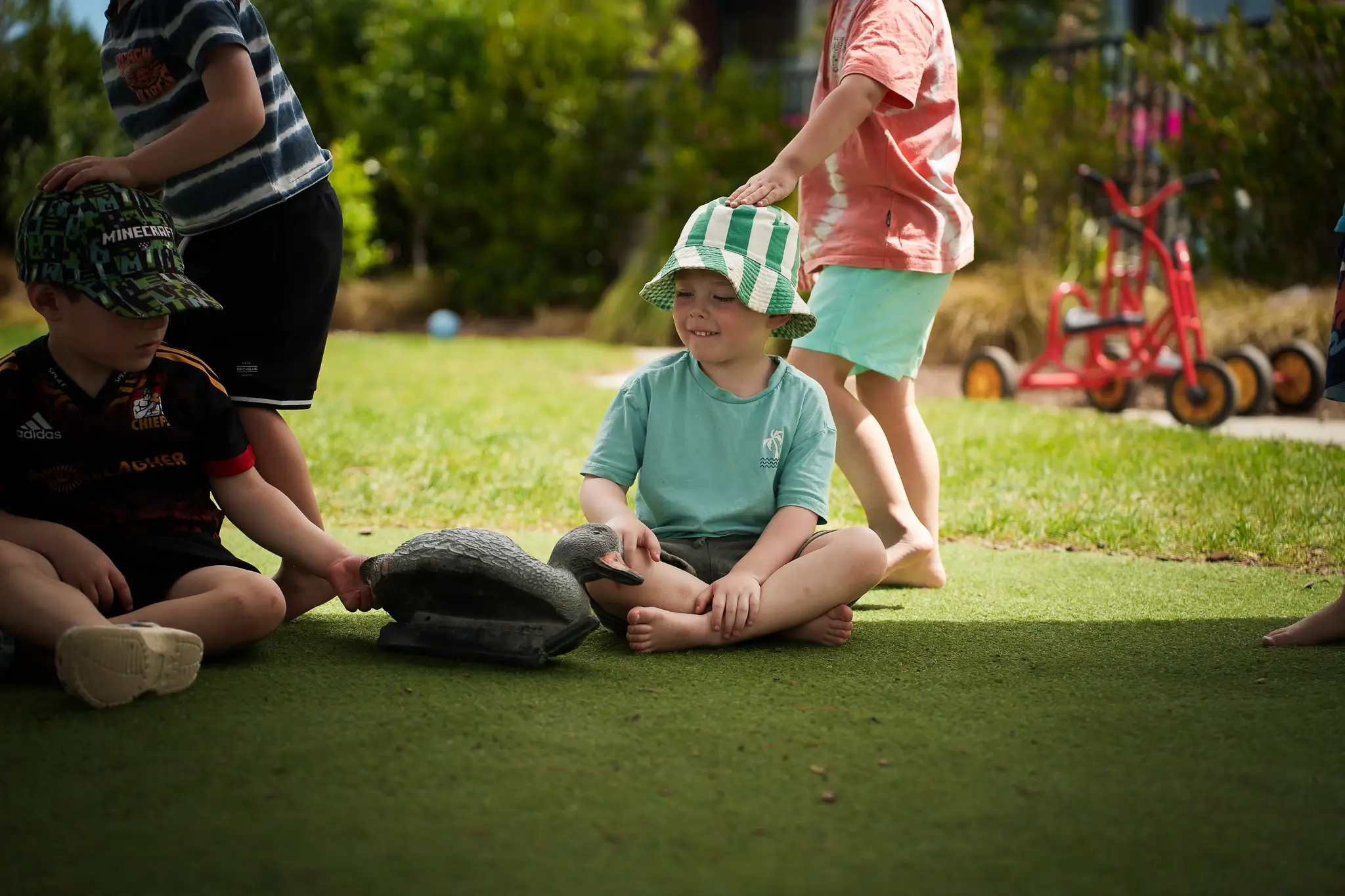 Young children engage in supervised water play with a teacher in an outdoor early childhood environment.