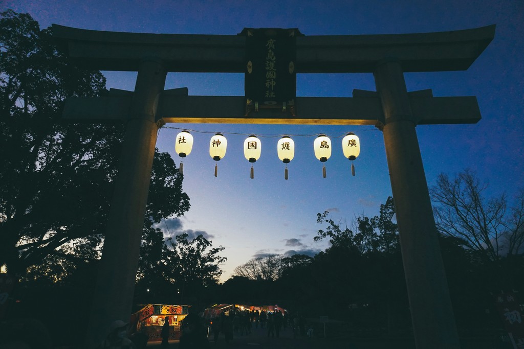 group of lanterns hanging from the bottom side of a tall tori gate