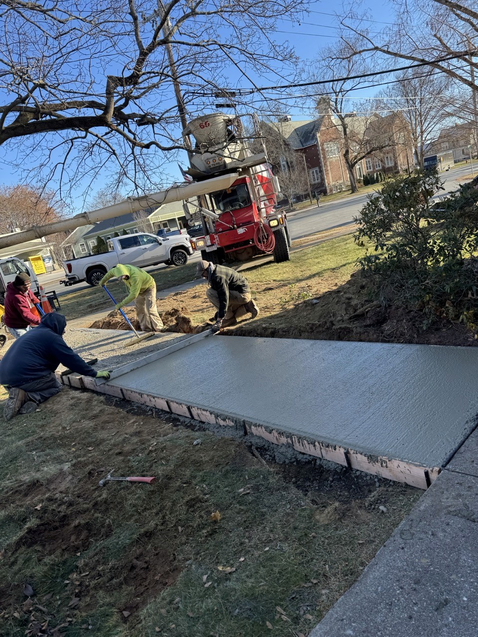 Crew finishing a fresh concrete sidewalk pour, by A&M Construction Enterprises
