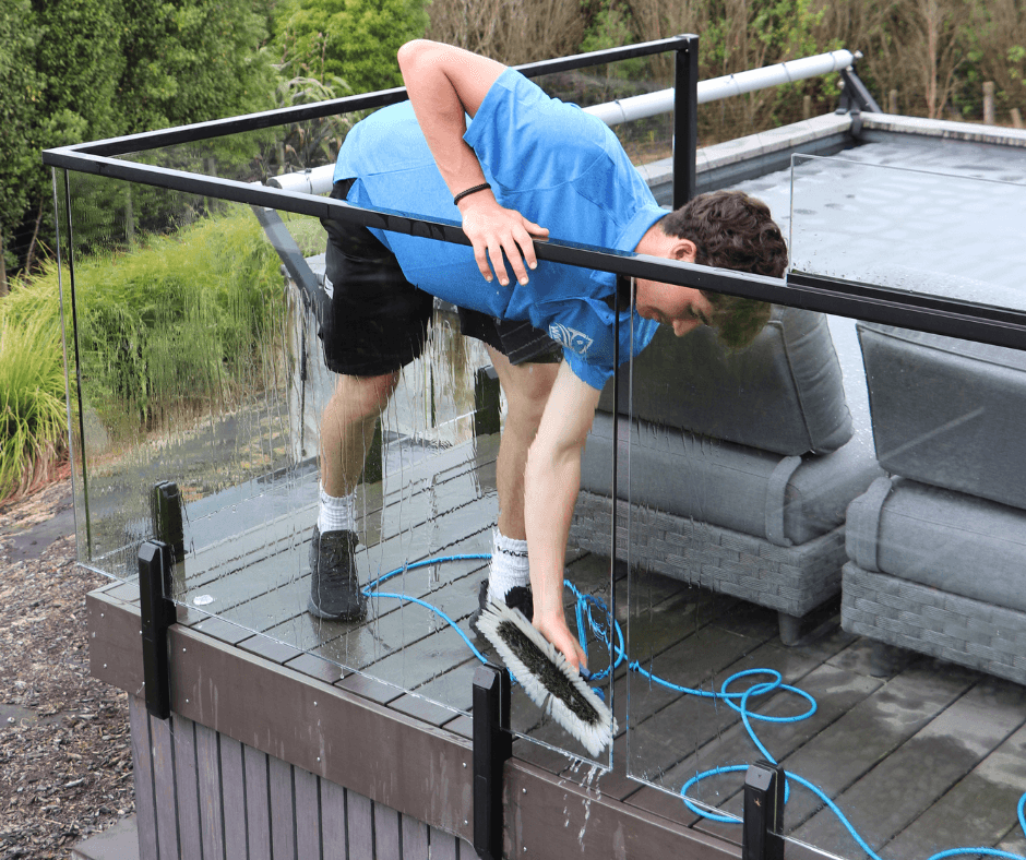 Team member detailing glass balustrade with purified water and squeegee as part of a full residential window cleaning service