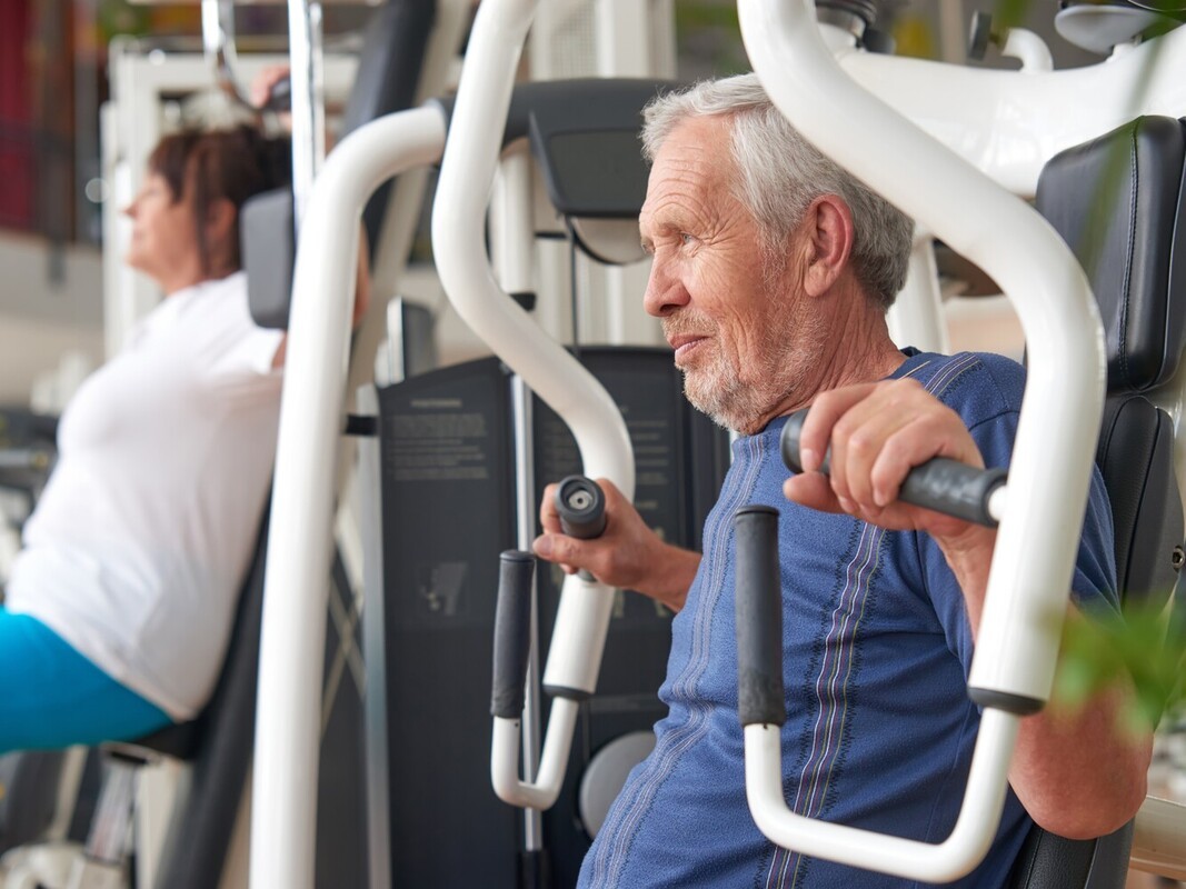 older man doing strength training exercises at the gym before using a sauna or steam room for weight loss