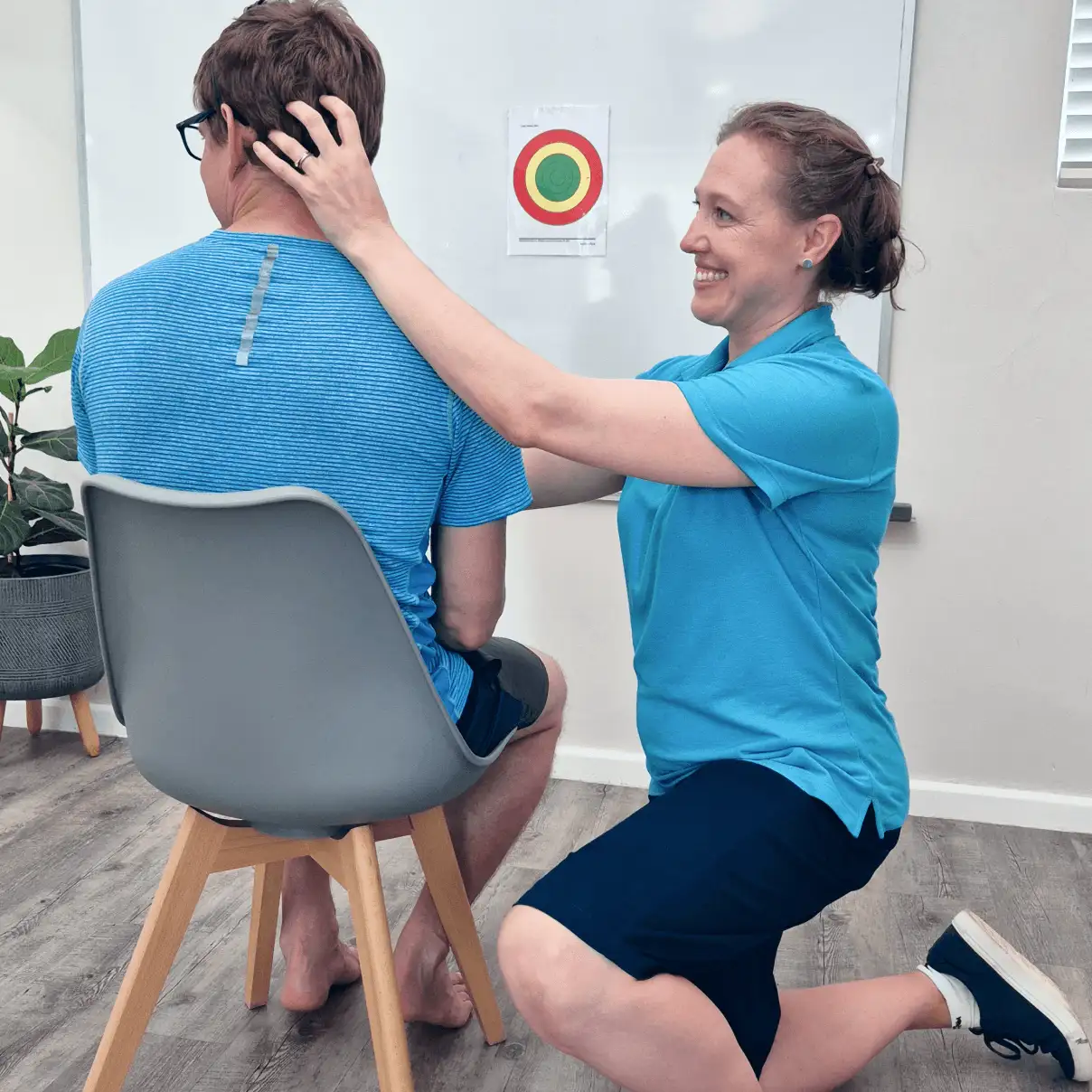 A Physiotherapist adjusts a patient head position to test neck movement with a Joint Position Error test on a patient 