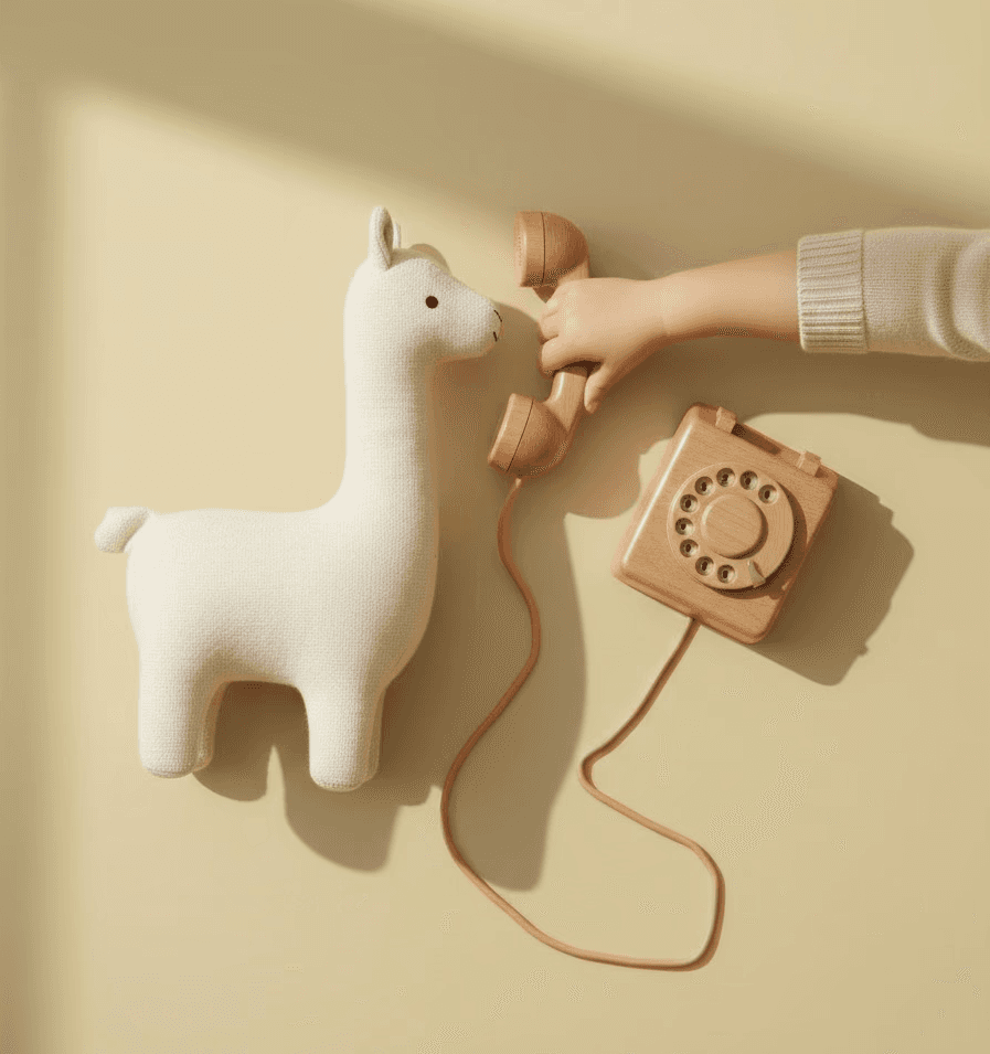 Toddler holding a wooden cable telephone for their lama toy.