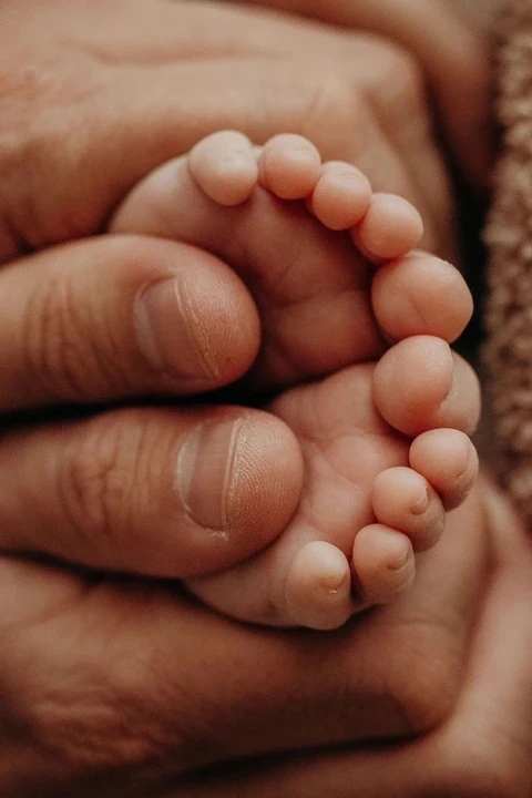 Baby toes peeking out between adult fingers