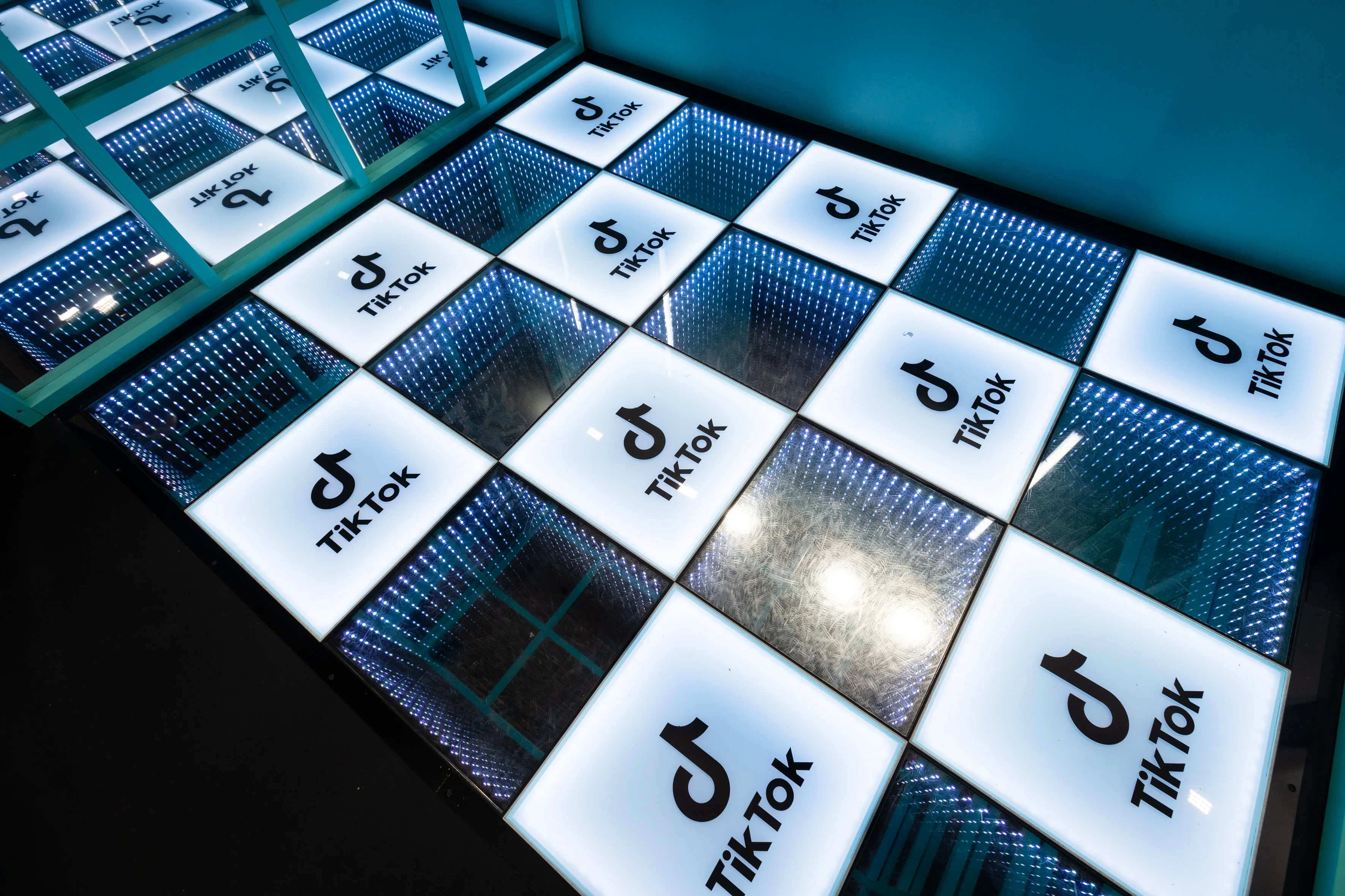 Walk-on checkerboard floor of glowing TikTok logo tiles and infinity-mirror panels.