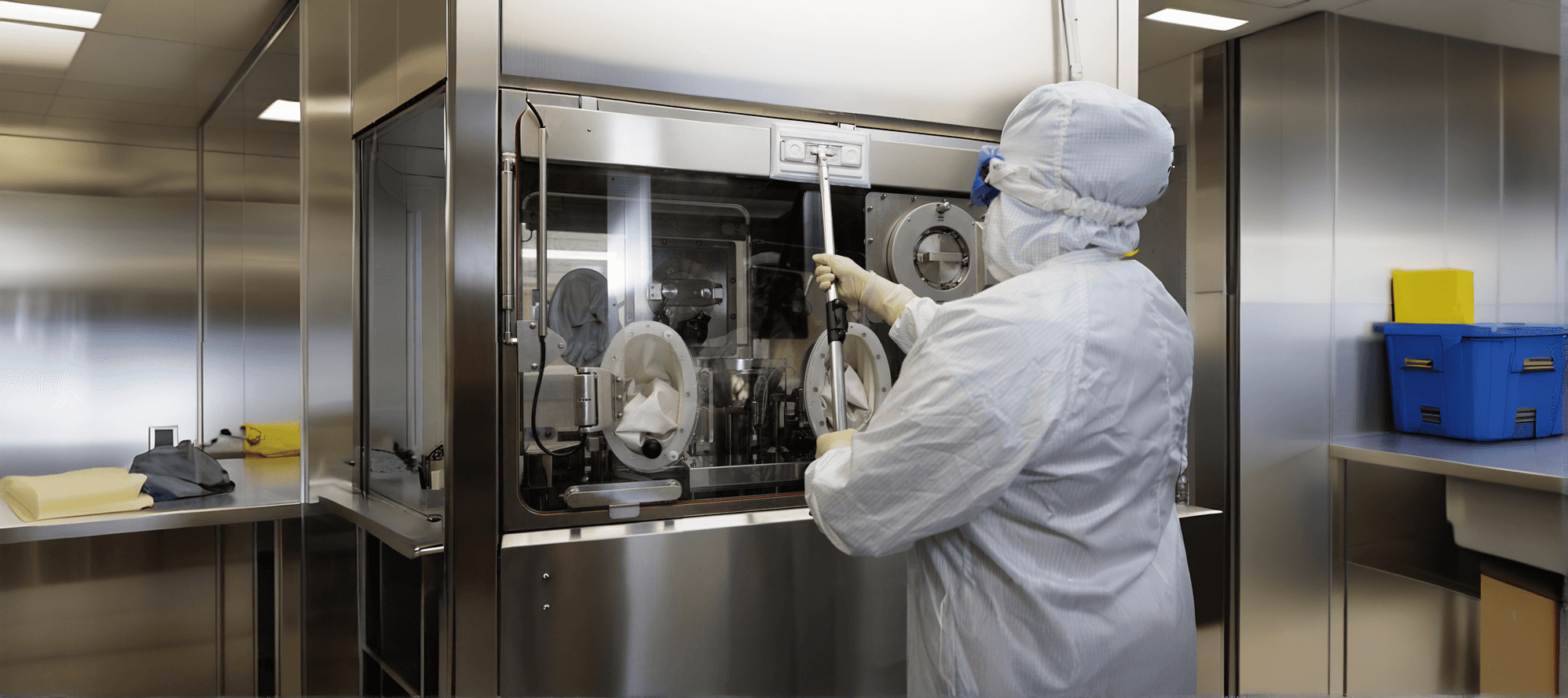Persona limpiando equipo en sala blanca de industria farmacéutica