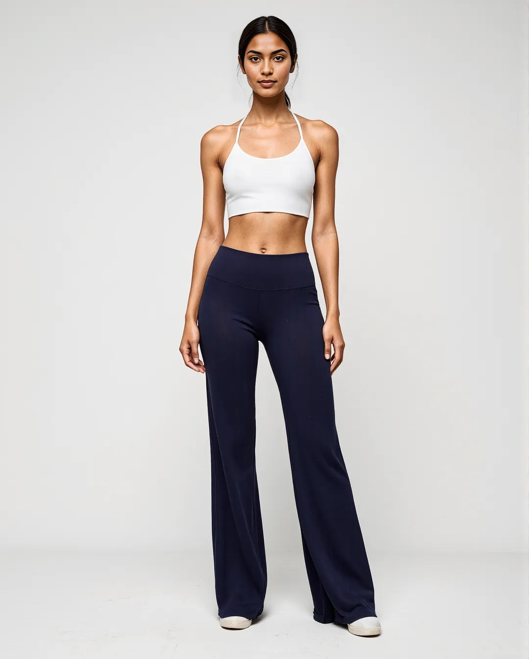 Professional athleisure wear photography featuring white crop top and navy wide-leg pants against minimal studio background