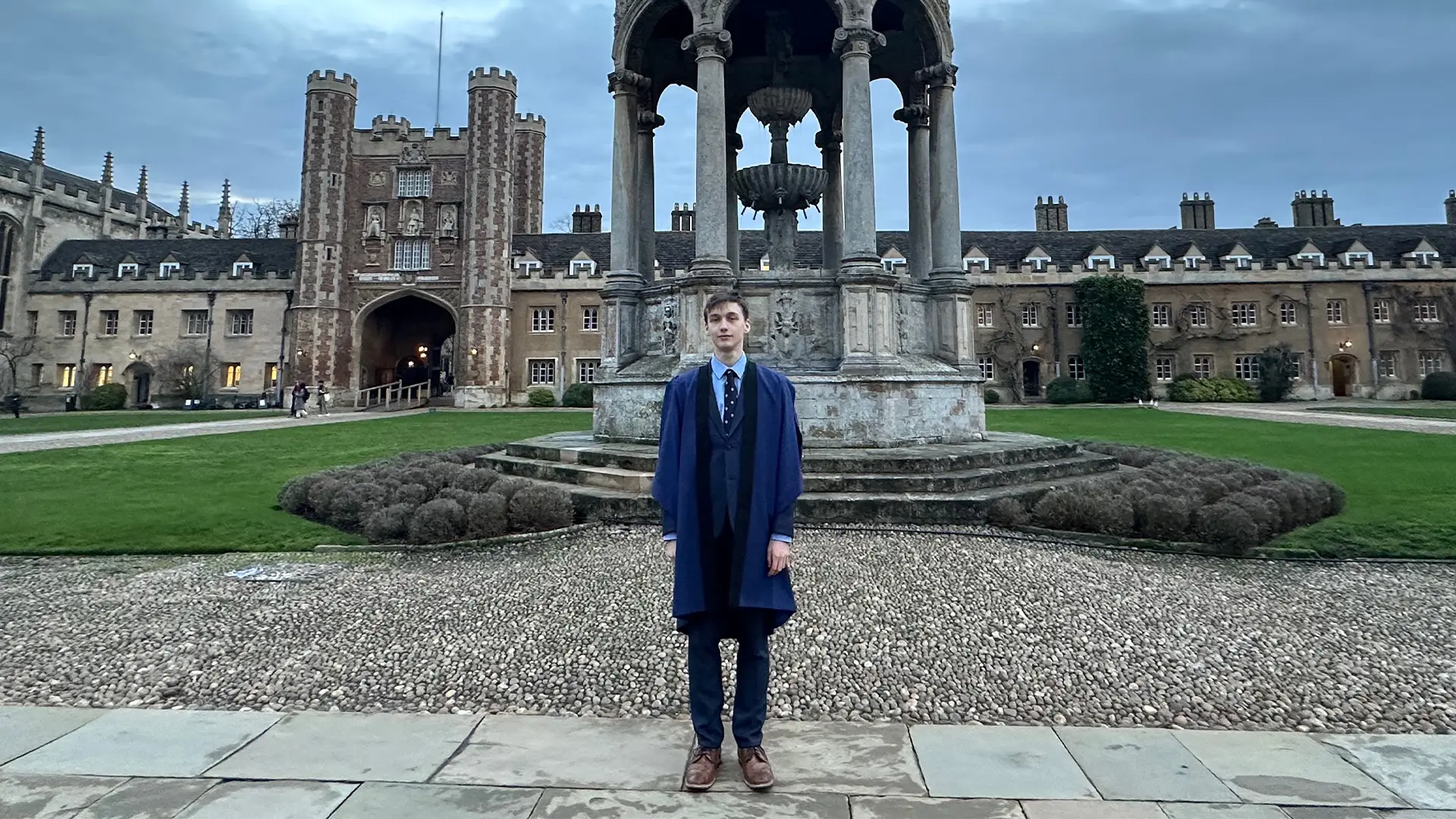 Student Jakub na nádvoří Trinity College v Cambridge u historické fontány a brány Great Gate.
