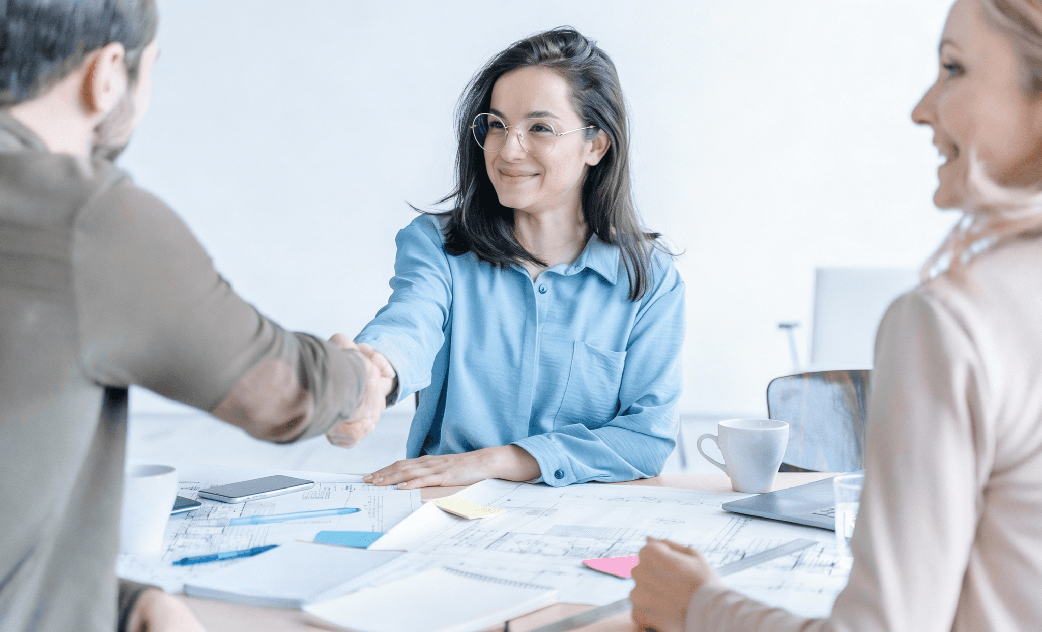 a man and a woman shaking hands in front of a laptop