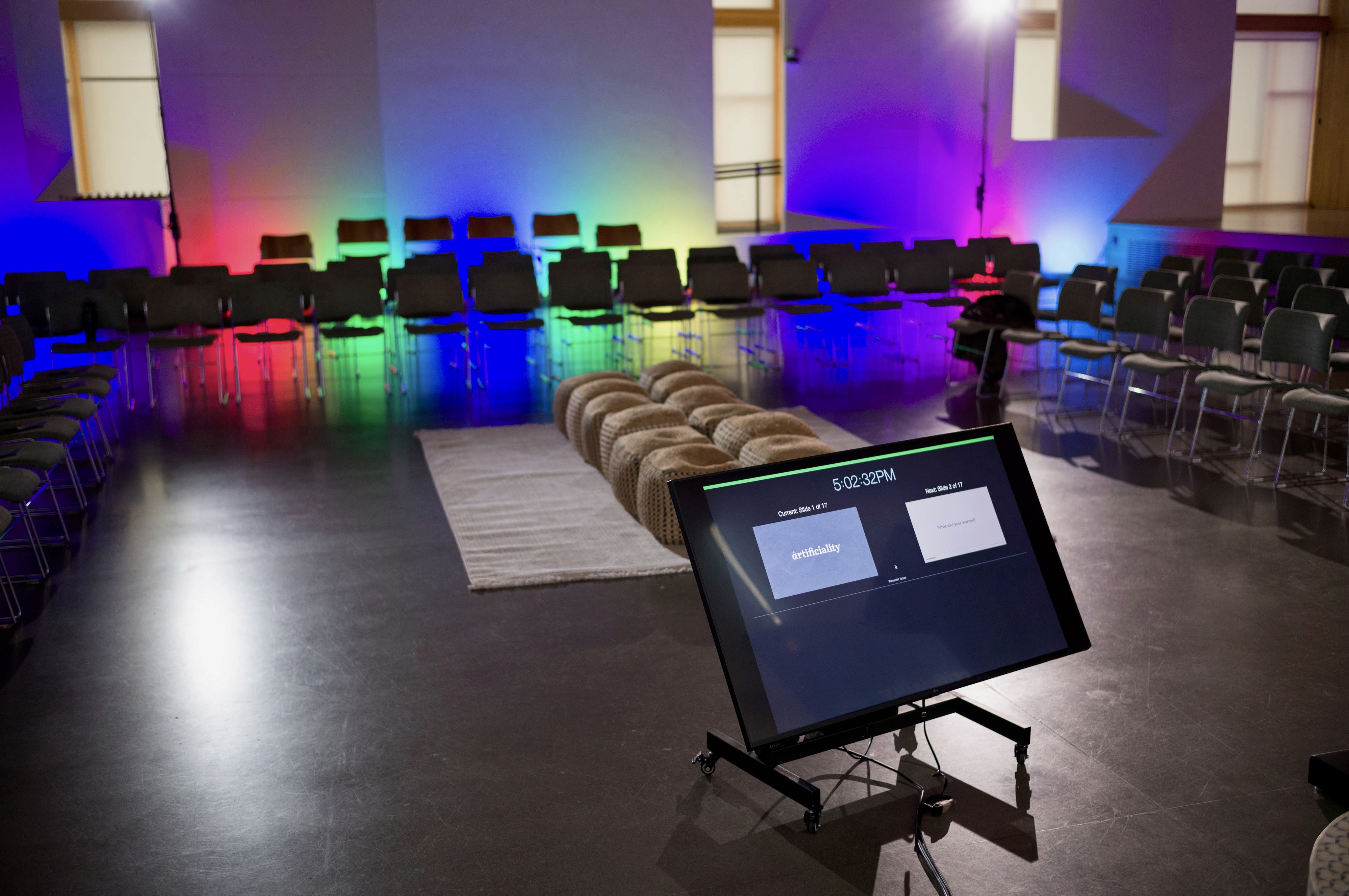 An room set for an event, the Artificiality Summit, with chairs and a confidence monitor.