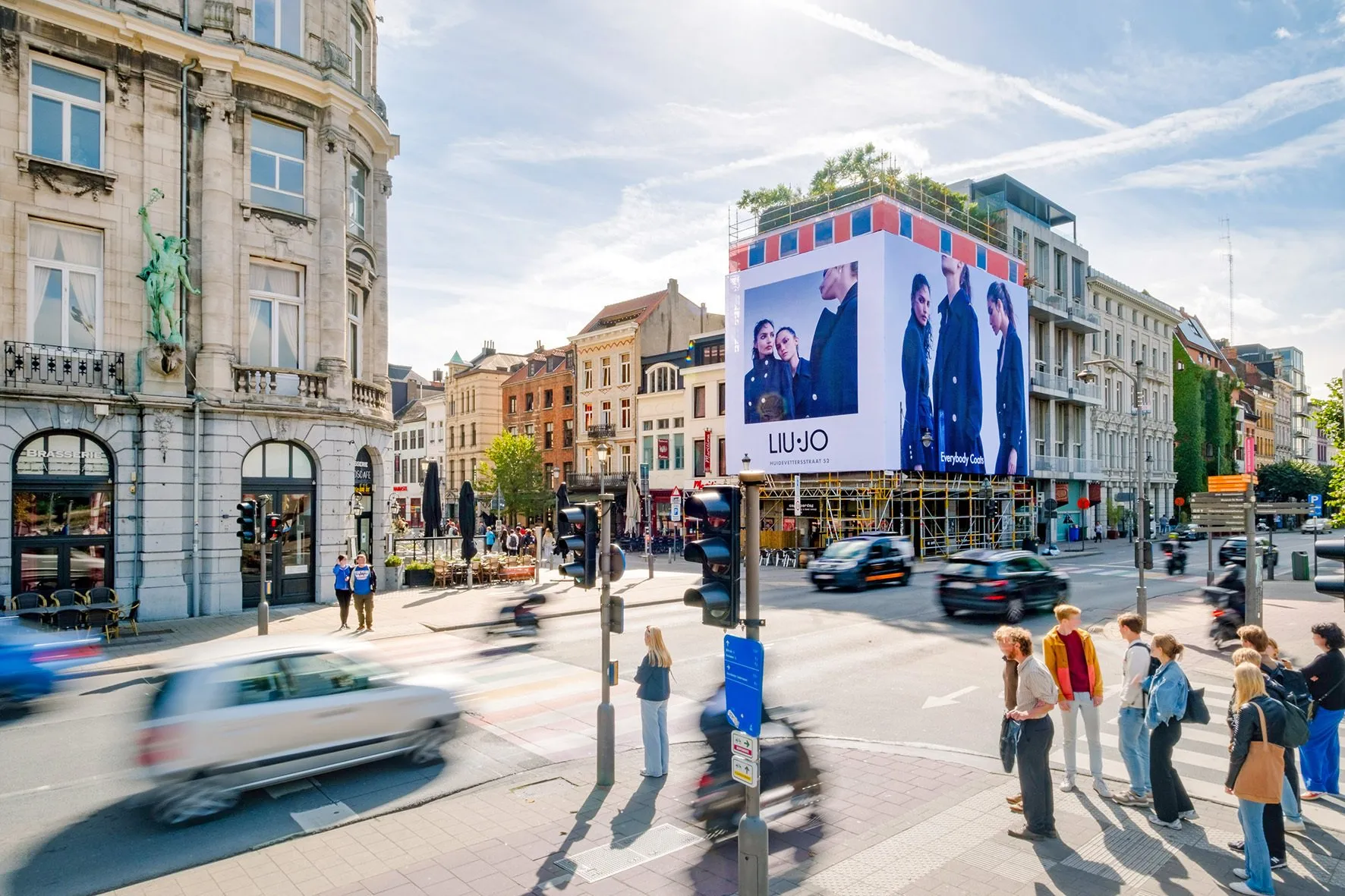a man walking down a street past a large poster