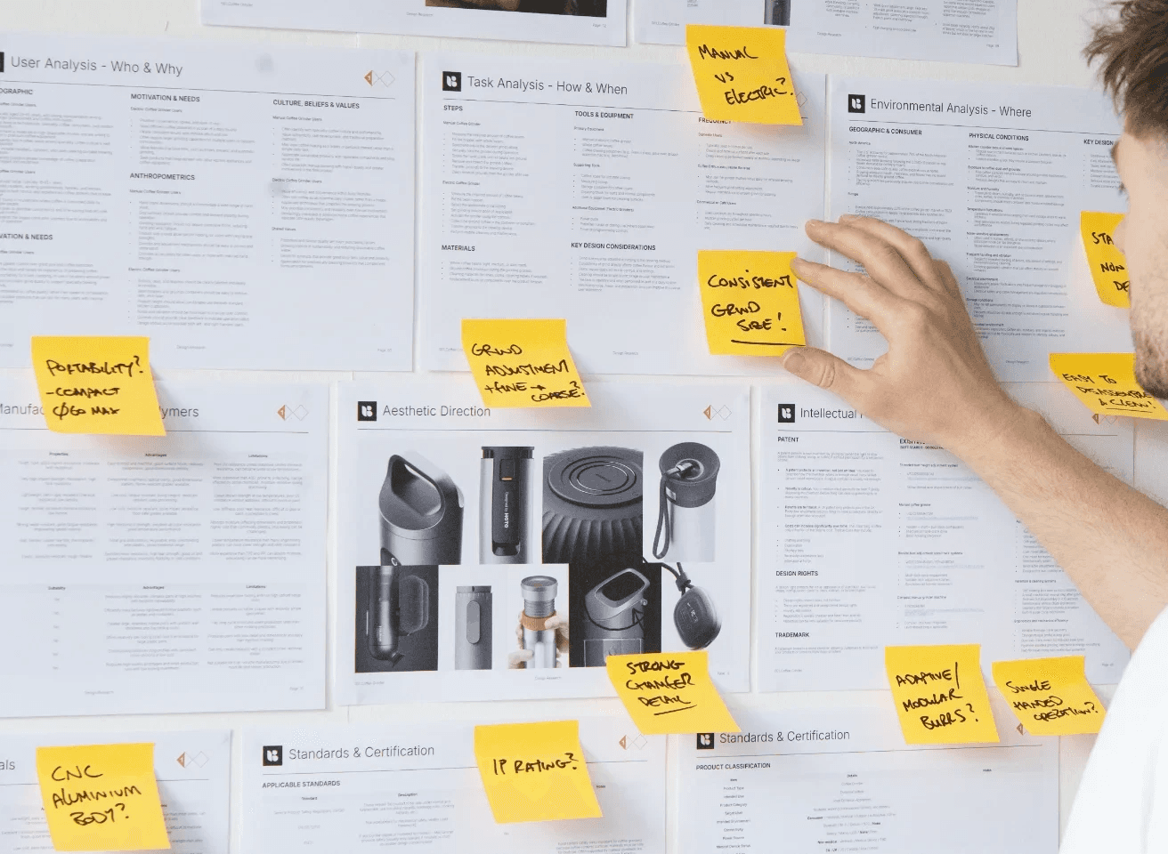 Industrial designer presenting and interacting with a design research board during a product development workshop.