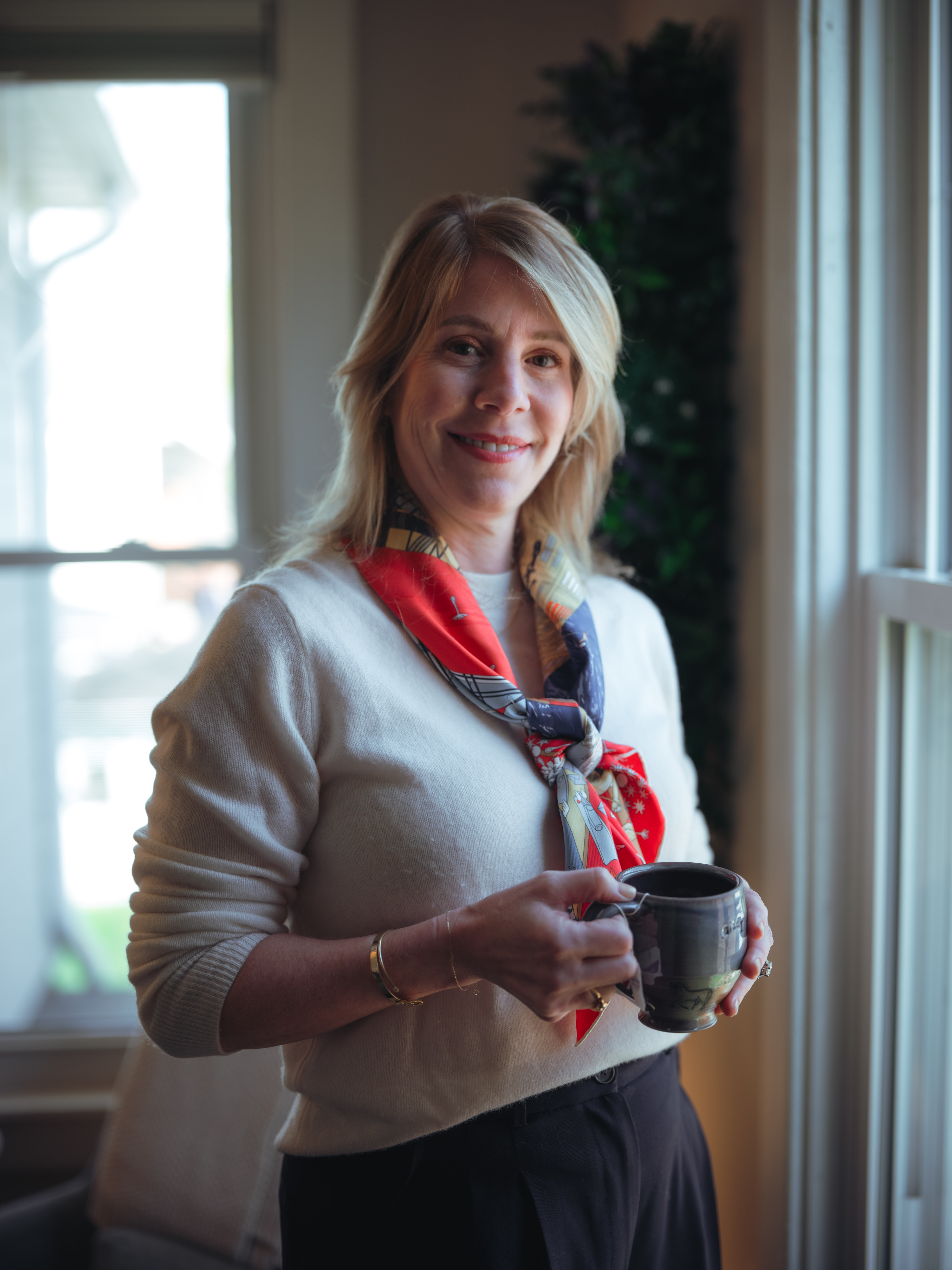 Woman holding coffee mug standing at window