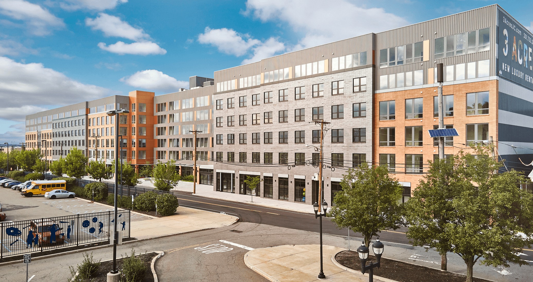 A modern commercial building surrounded by trees and blue skies, featuring glass facades and an urban setting.