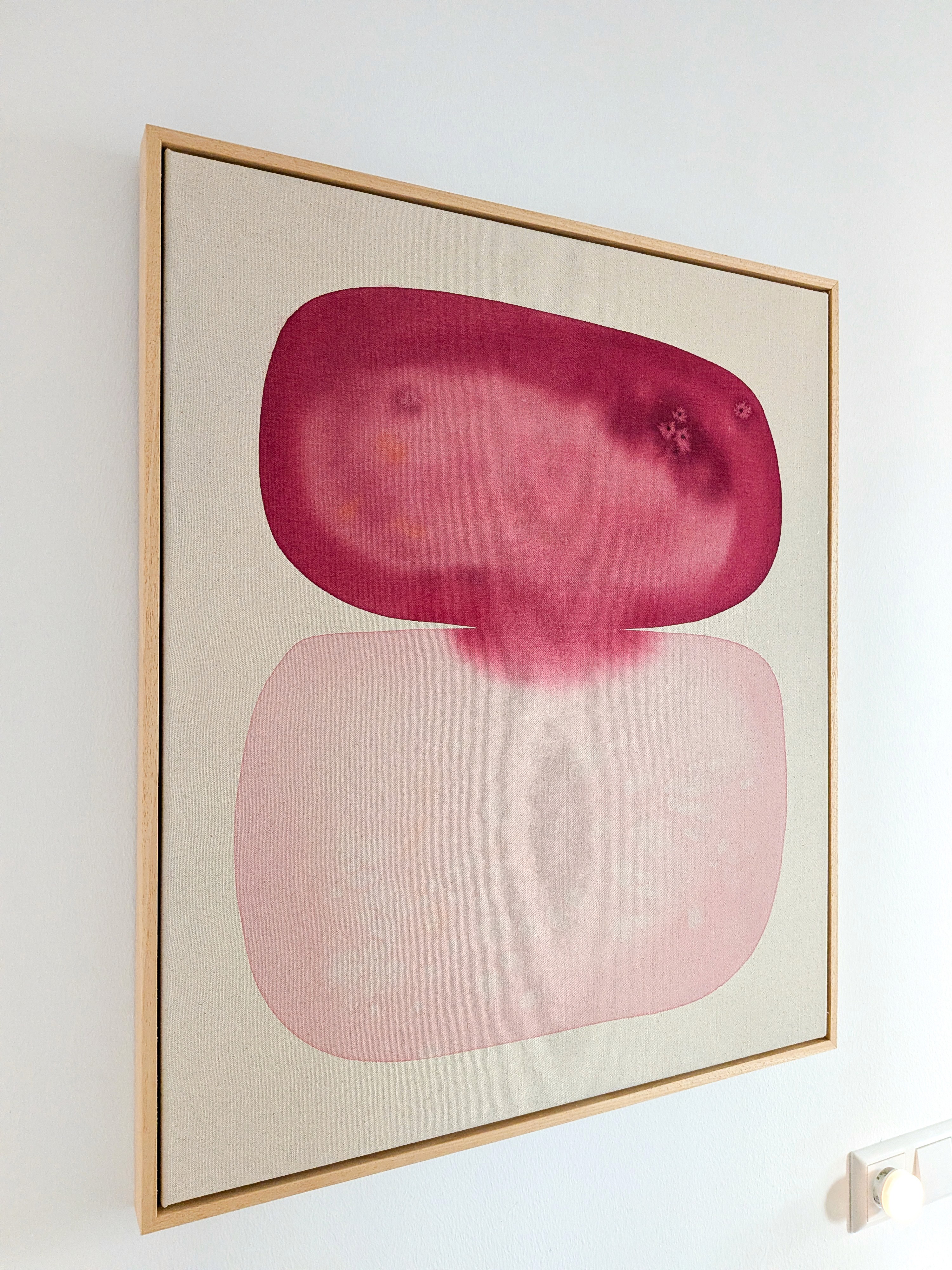 Abstract art piece featuring layered shapes in shades of pink and red against a light background.
