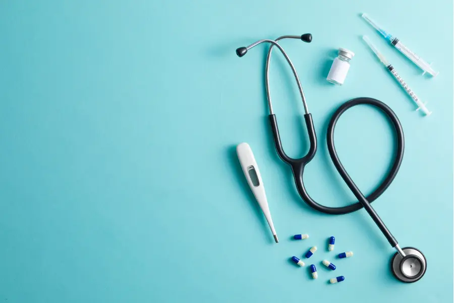 AI in the pharmaceutical industry represented by stethoscope, syringes, pills, and medical tools on blue background.