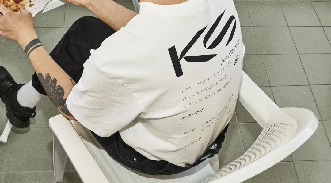 Handsome man in chair, wearing Komea Stock T-shirt