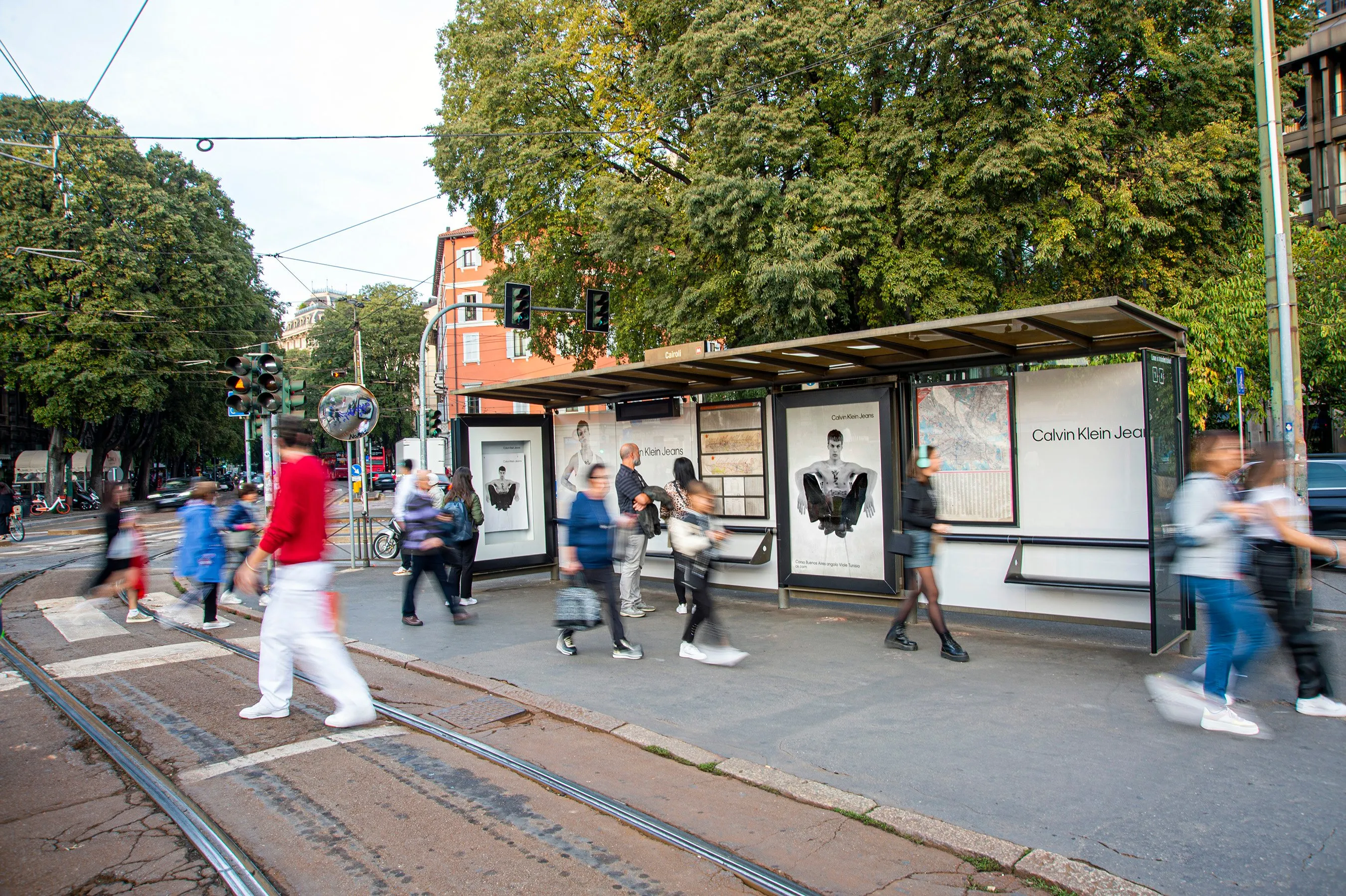 a man walking down a street past a large poster