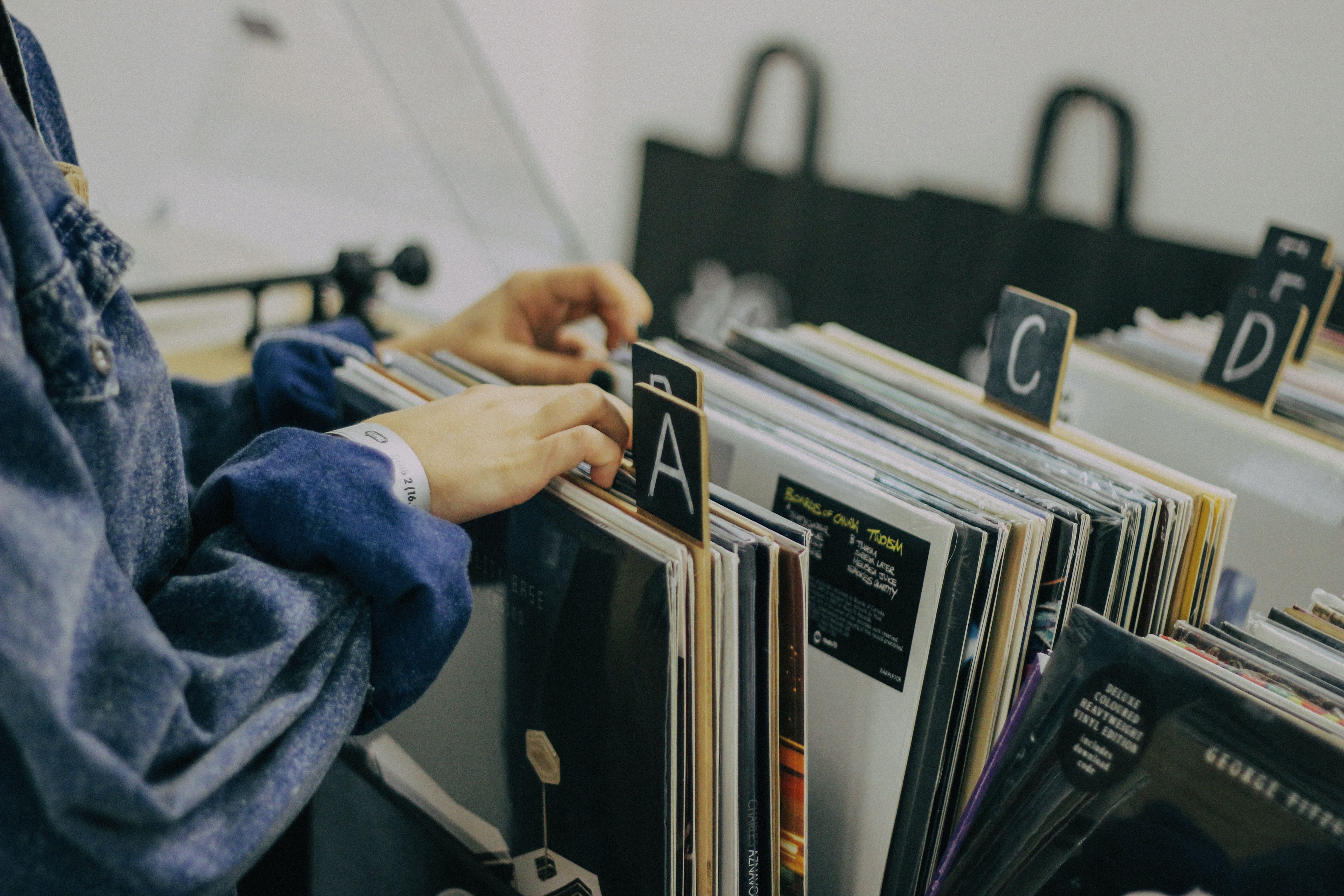 Person browsing vinyl records in a record store organized alphabetically