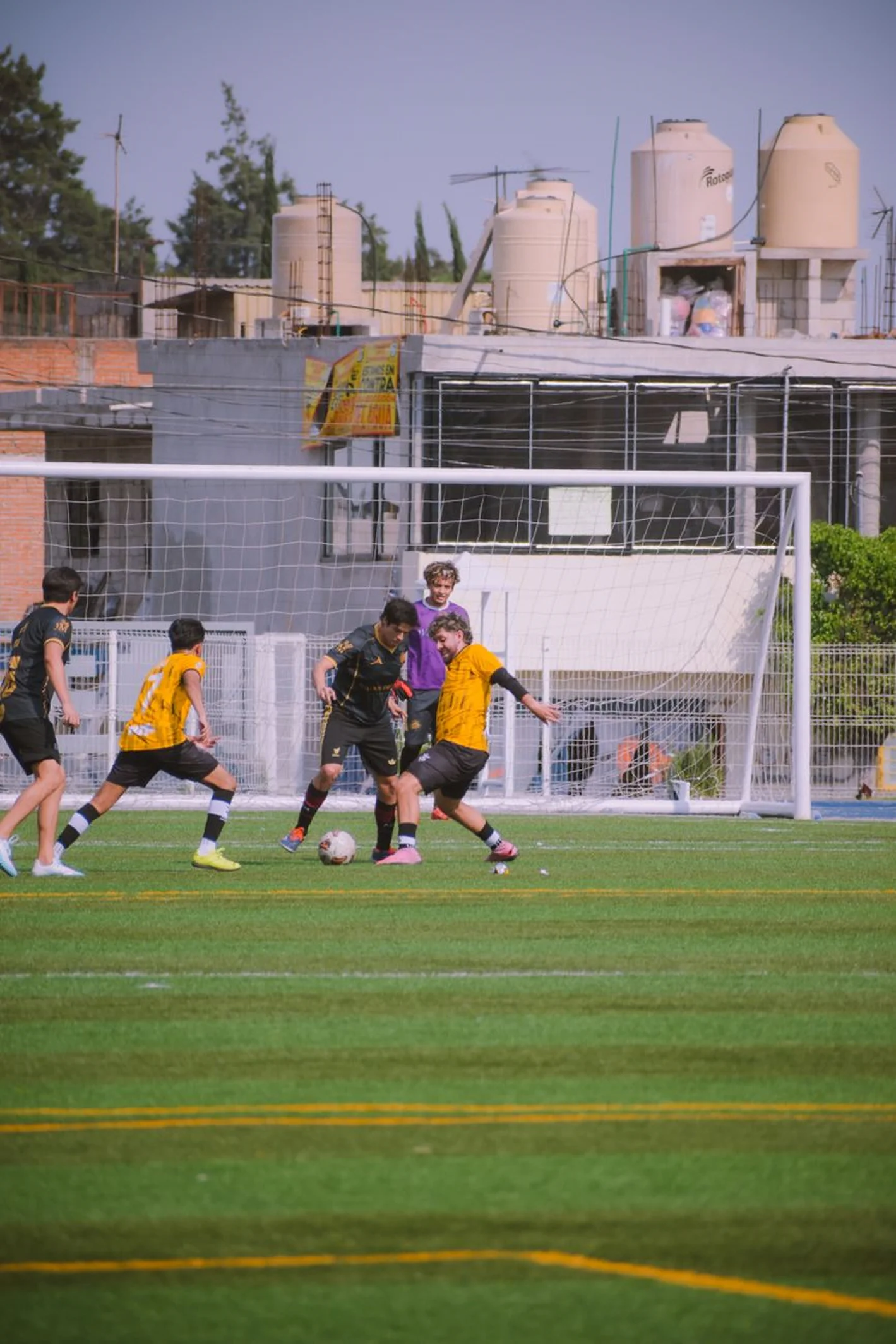 Players competing near a soccer goal on artificial turf