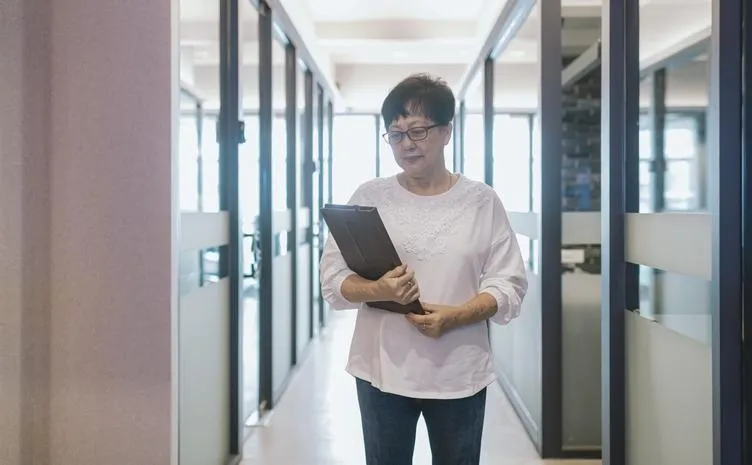 Asian businesswoman holding a tablet in a modern office hallway
