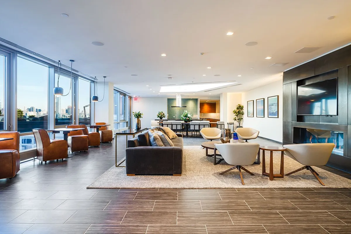 A modern living room in a New York City apartment, featuring a sofa, coffee table, and large windows with city views.