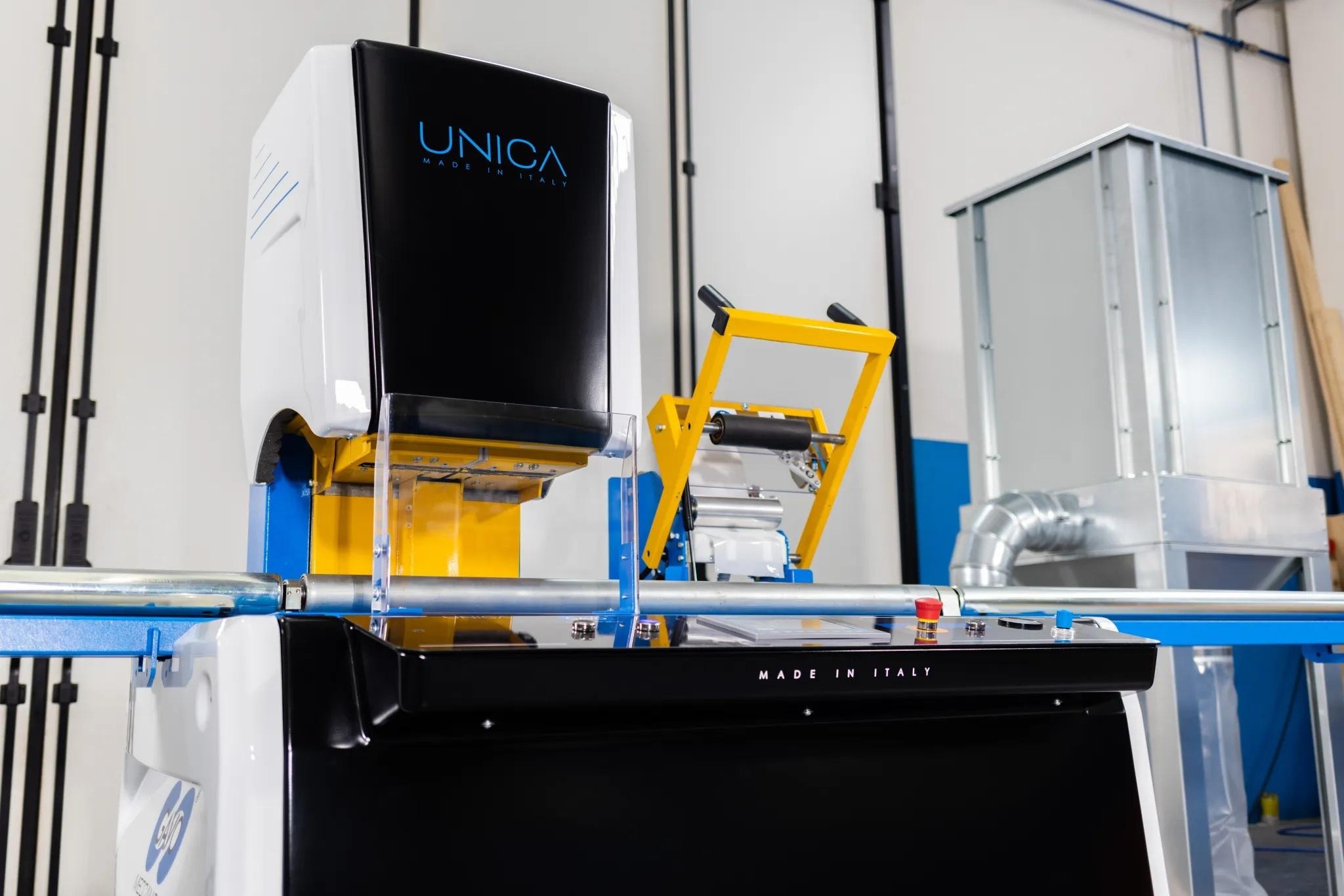 Close-up of UNICA industrial core cutting machine with automated reel handling system in manufacturing facility.