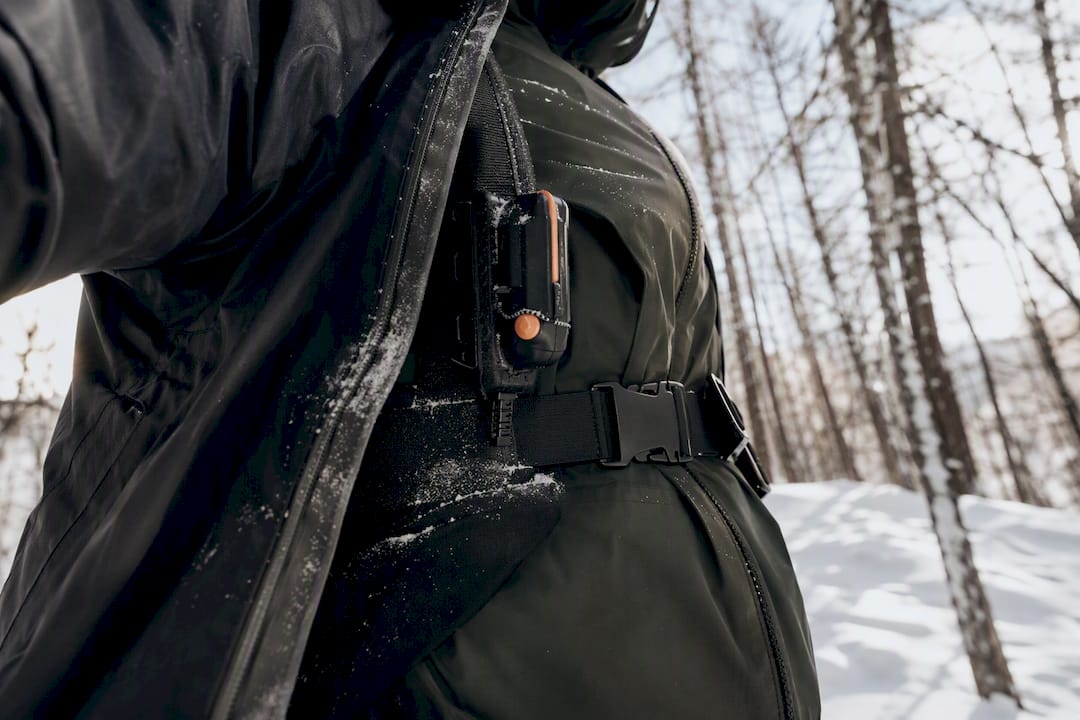 Person wearing an avalanche transceiver harness beneath an outdoor jacket