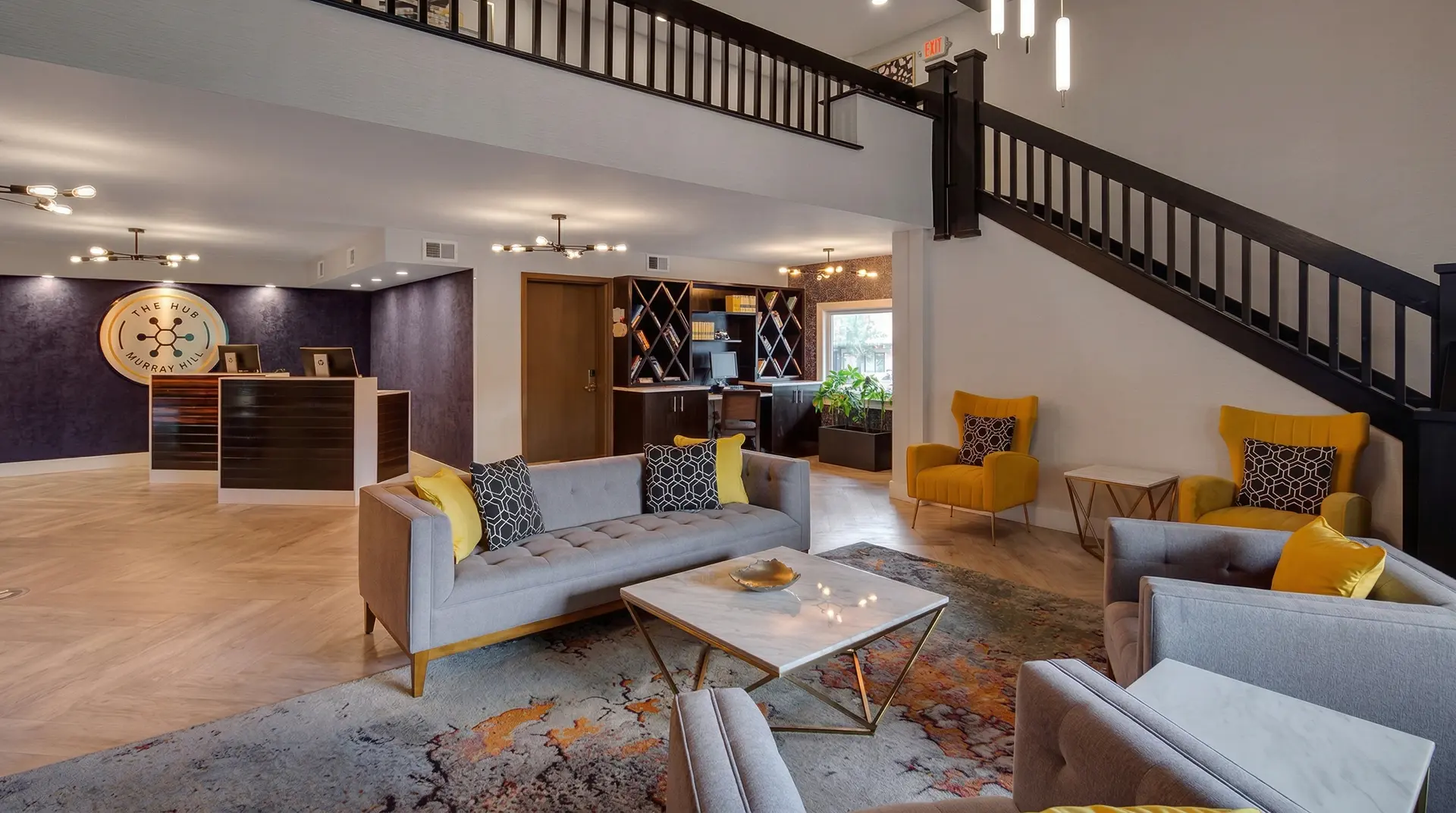Modern lobby with a reception desk, grey sofa, and yellow armchairs.