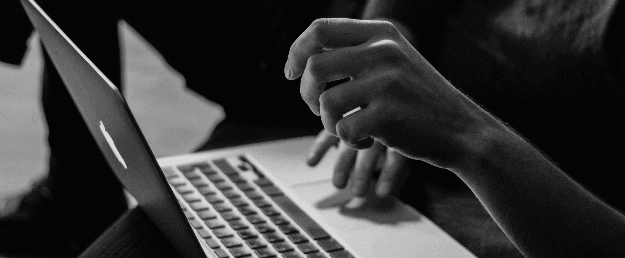 Black and white close up of a hand working on a laptop