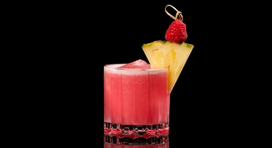 A closeup of a Sweet, Summer 4th of July Sunrise drink against a dark background.