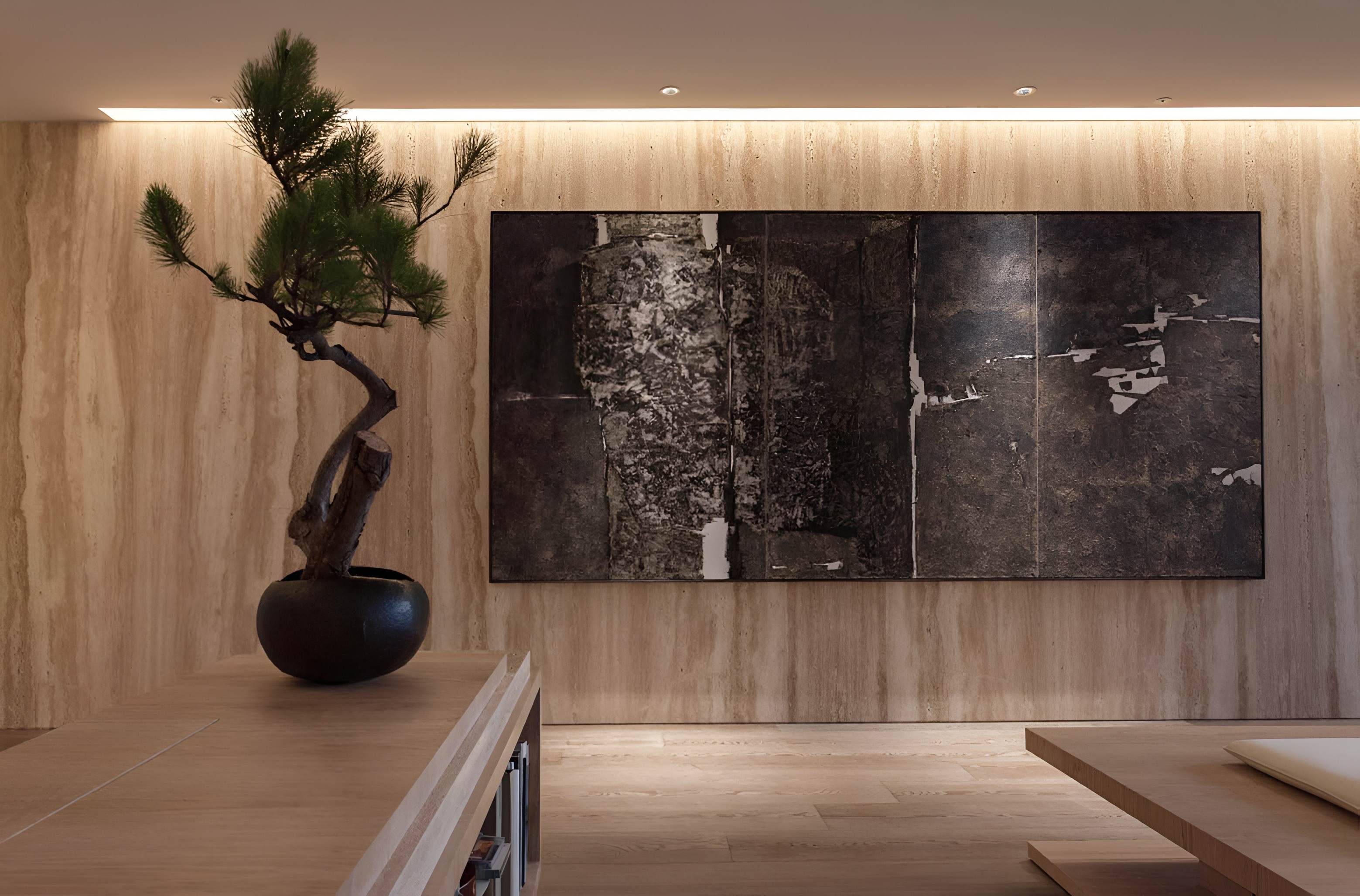 一株造型松樹盆景擺放於木櫃上，背景為大型抽象畫作與淺色石材牆面