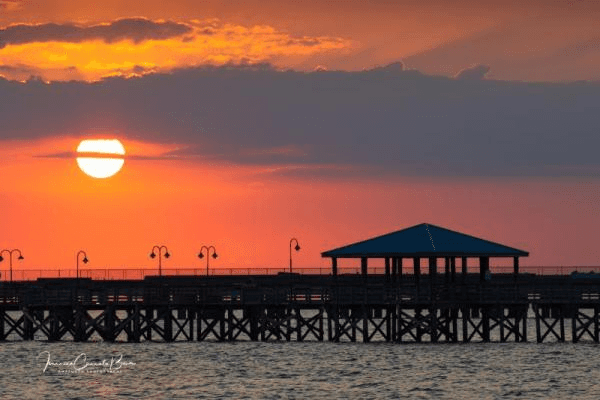 Beautiful orange sky sunset over Lake Ponchartrain showing a pier at The Lake Front in Mandeville Louisiana