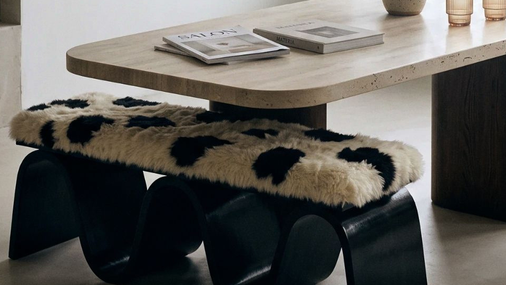 The same image at 100 %: wool pile, travertine edge with its pores and the dark oak pedestal
