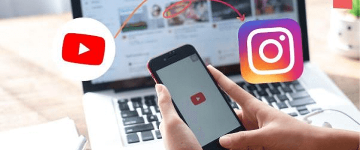A hand holding a smartphone showing the YouTube app with Instagram and a laptop in the background, representing how to repurpose a corporate video for maximum ROI.