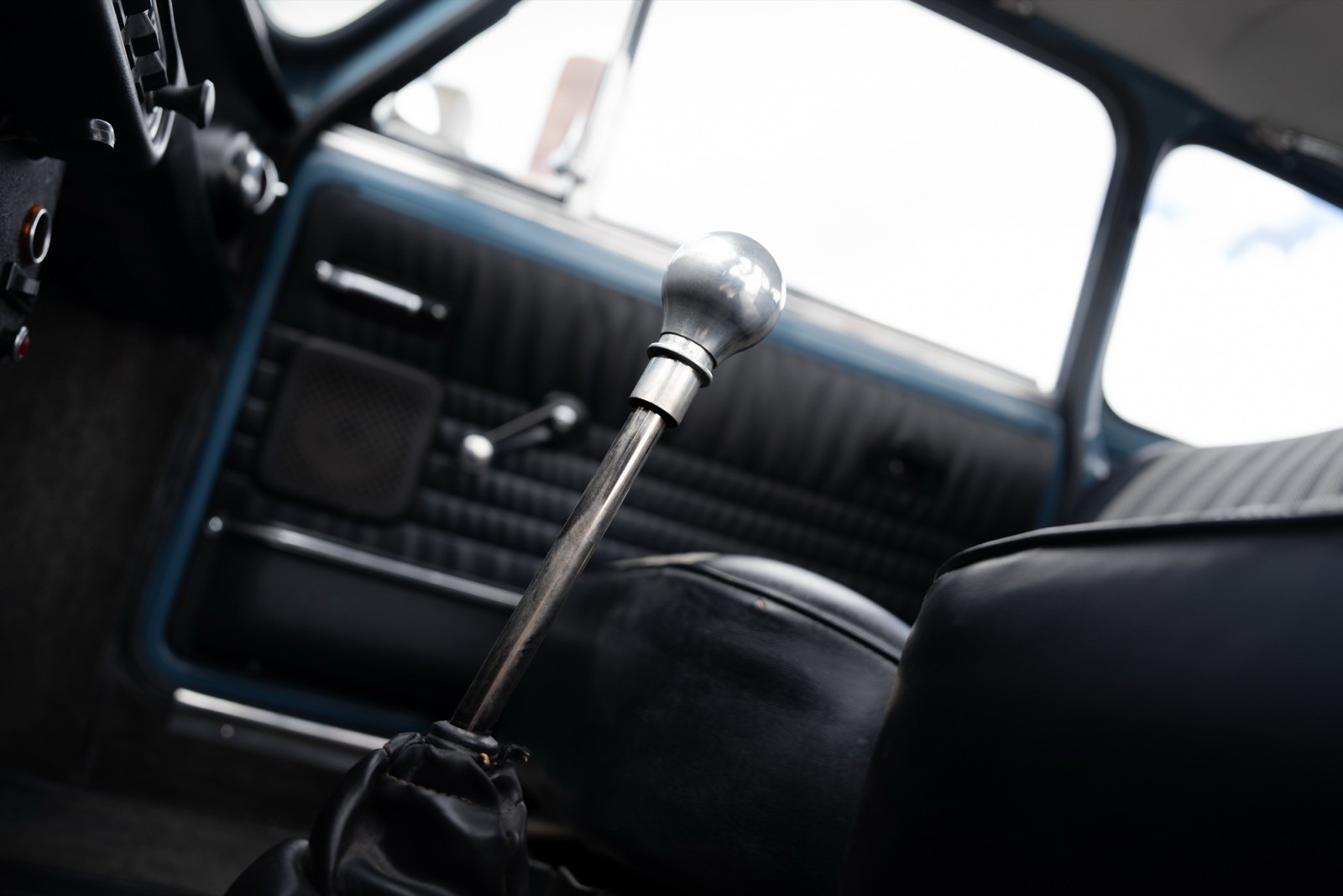 Interior of a car showing the gear shift, dashboard, and door panel. Natural light coming through the window.