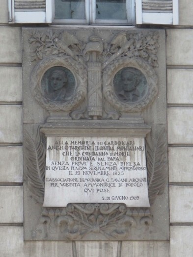 A photo of an engraved wall with writings and stone figures on it.