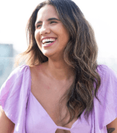 Foto de Laryssa Bolele. Ela sorri, olhando para o lado e está usando uma blusa lilás.