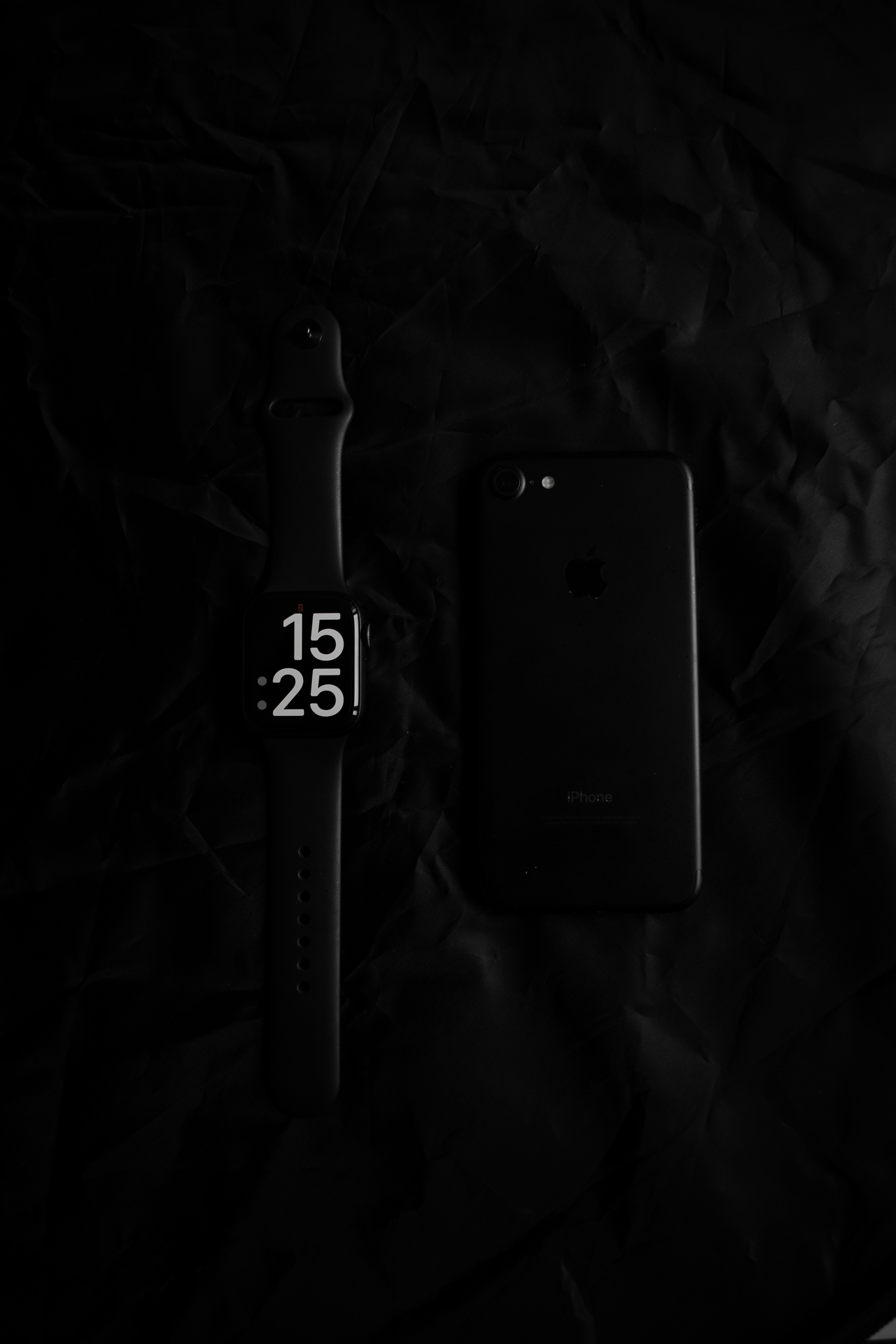 a cell phone and a watch on a black background