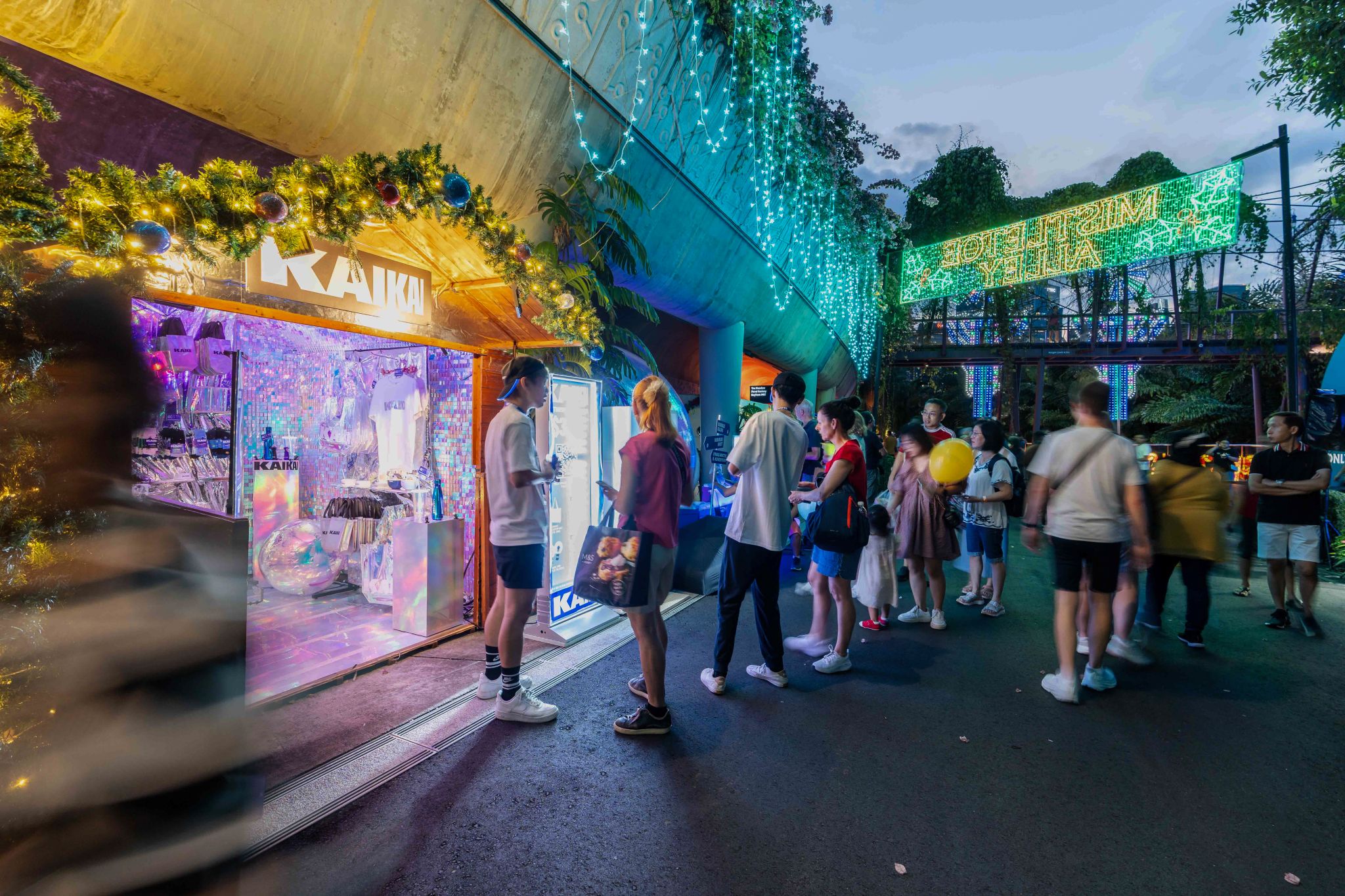 Smiling young man with short hair poses against a dark background, wearing a green button-up shirt.