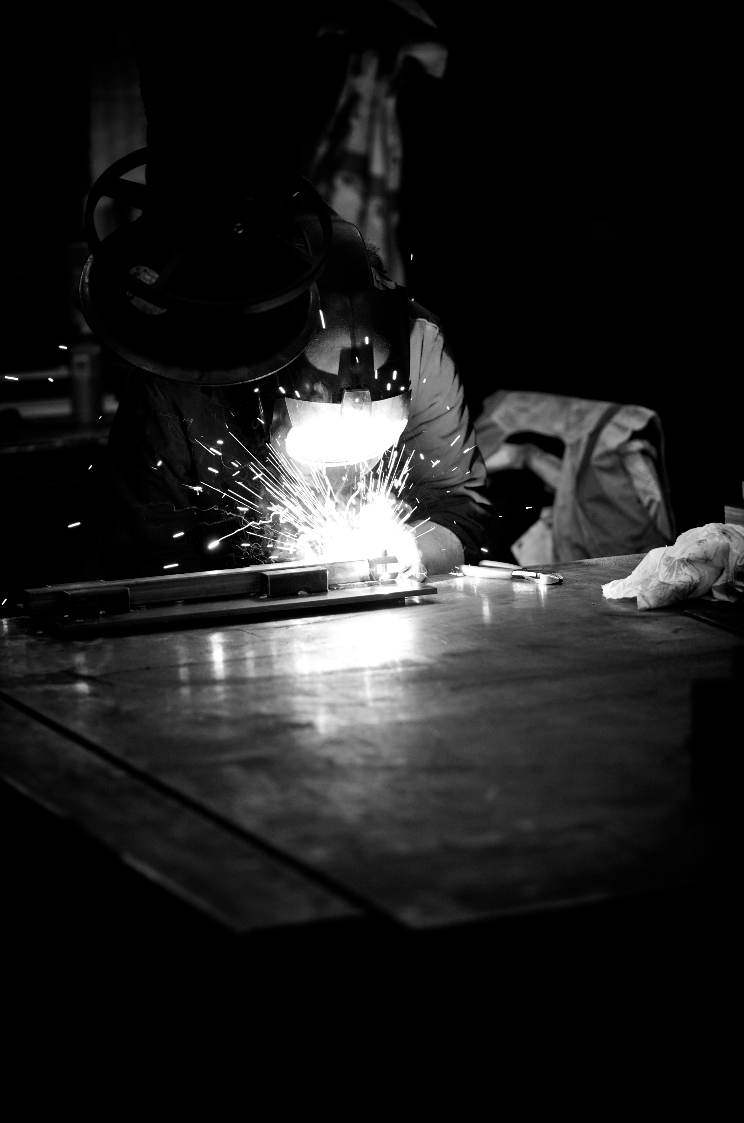 Welder is working, creating sparks in the dark.