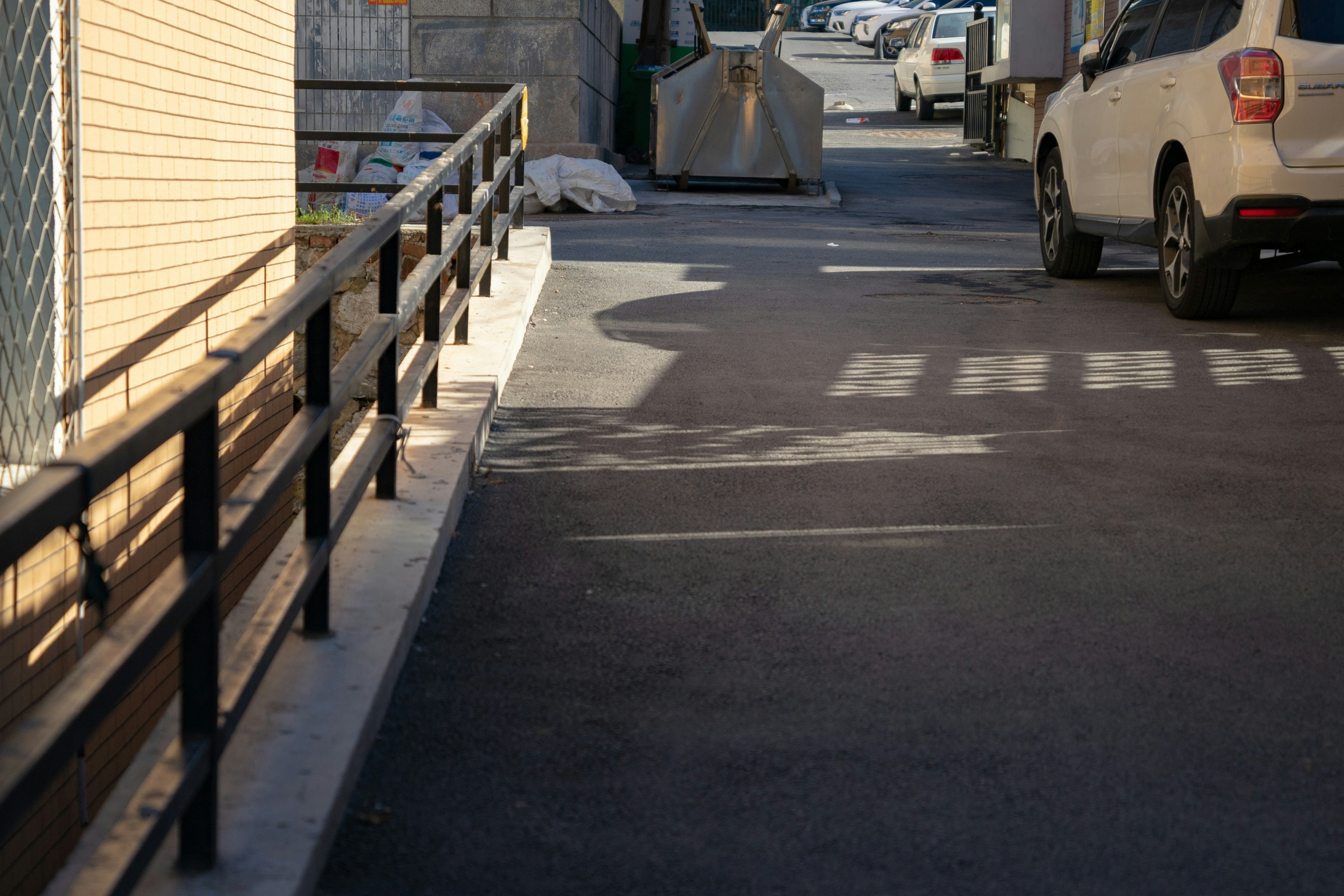 Rampe d’accès en béton avec garde-corps noirs le long d’un bâtiment commercial.